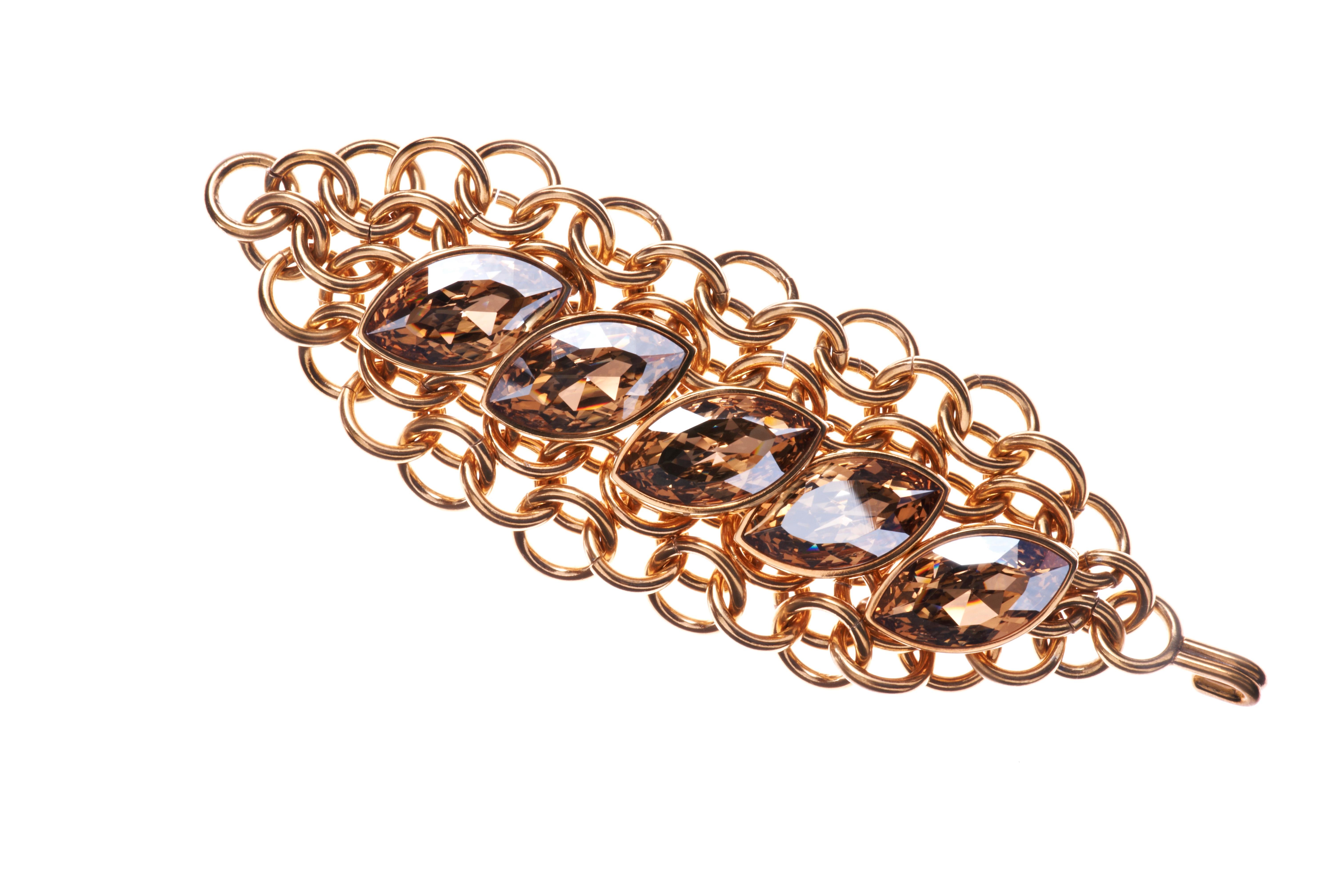 A dramatic fusion of handmade chainmail and Swarovski crystal creates a bold statement bracelet. The chainmail drapes and embraces the wrist perfectly, working well with denim to duchesse silk. The bracelet is finished in 24 carat gold with