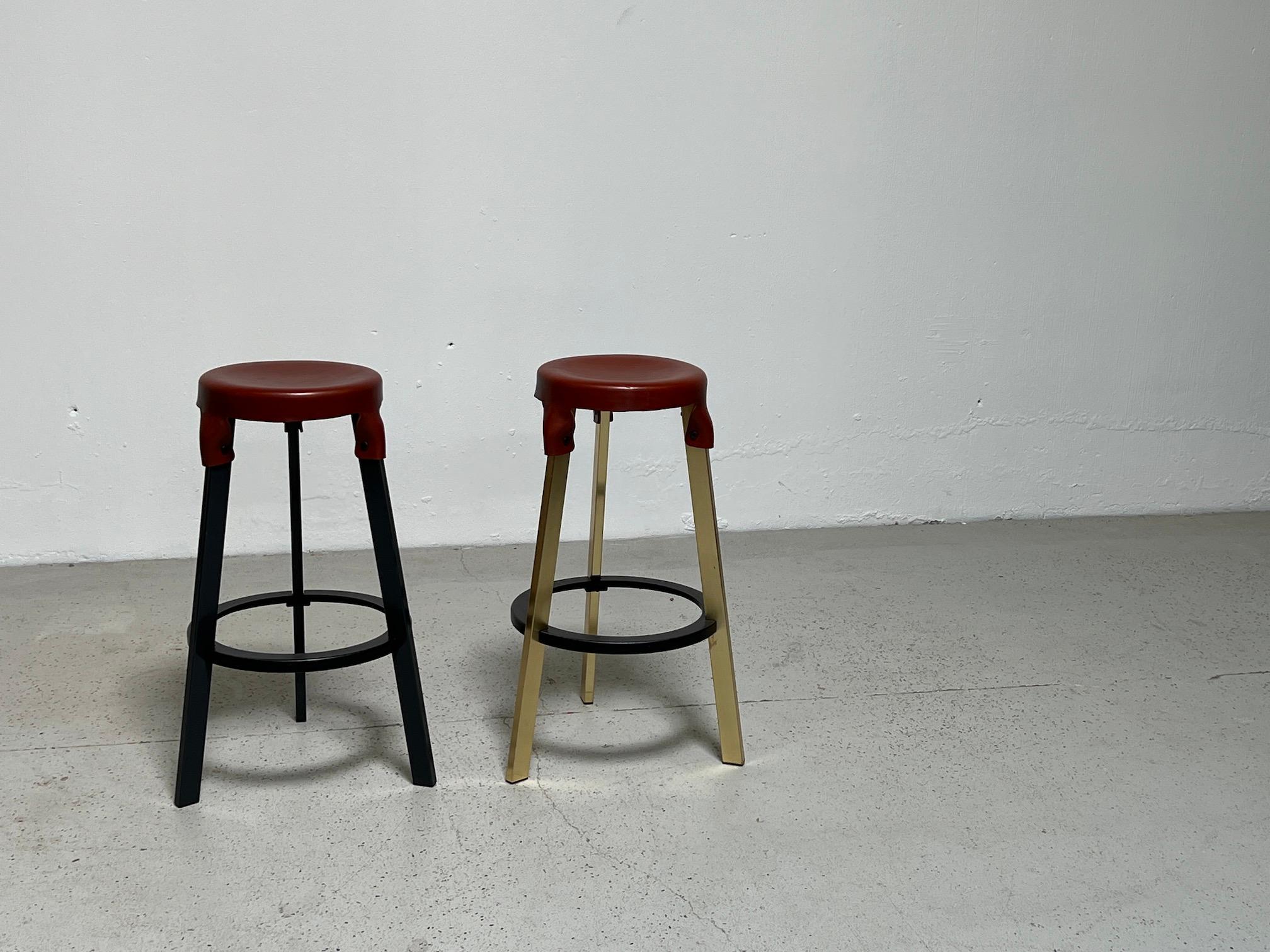 Leather top bar stools by Simon Hasan. One stool with a brass base and one with a black base. Priced and sold separately.