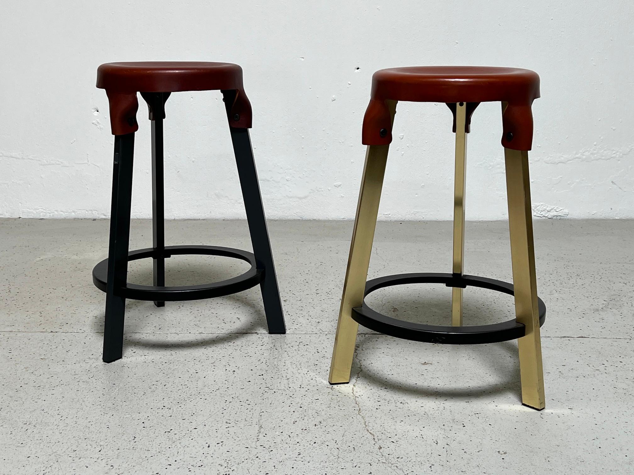 Leather top counter stools by Simon Hasan.  One stool with a brass base and one with a black base. Priced and sold separately. 