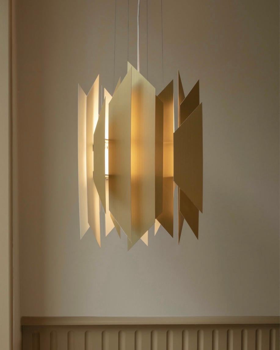 The new edition of the DIVAN 2 pendant in solid brass shimmers and glows without being flashy. Thanks to the carefully positioned trapezoids, the pendant provides a comfortable glare-free light while cascading indirect light into the room by