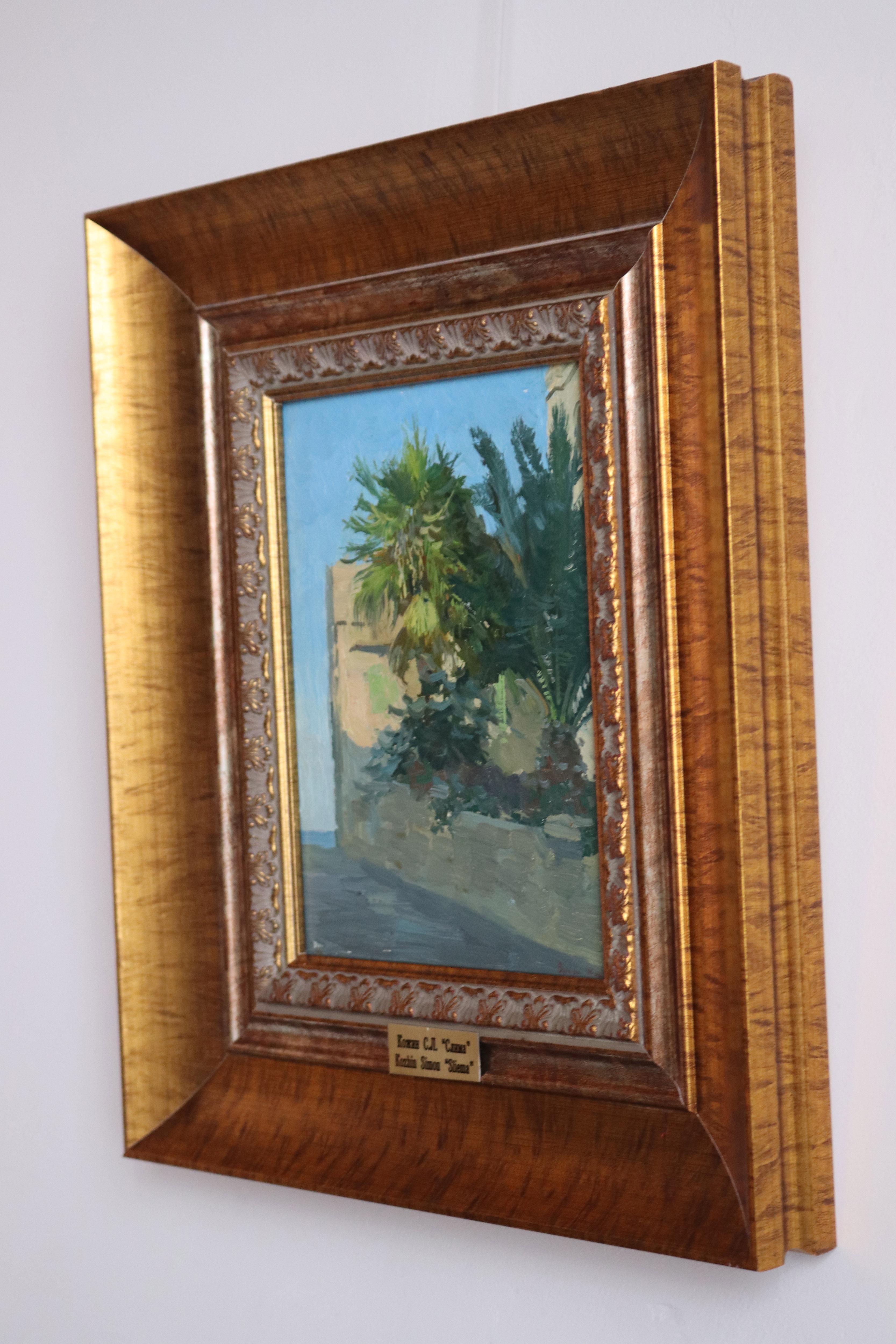 A vibrant street scene features lush green palm trees against the backdrop of a clear blue sky and a building with muted tones. The composition captures the serene atmosphere of a sunny day, with natural elements in harmony with the architecture.