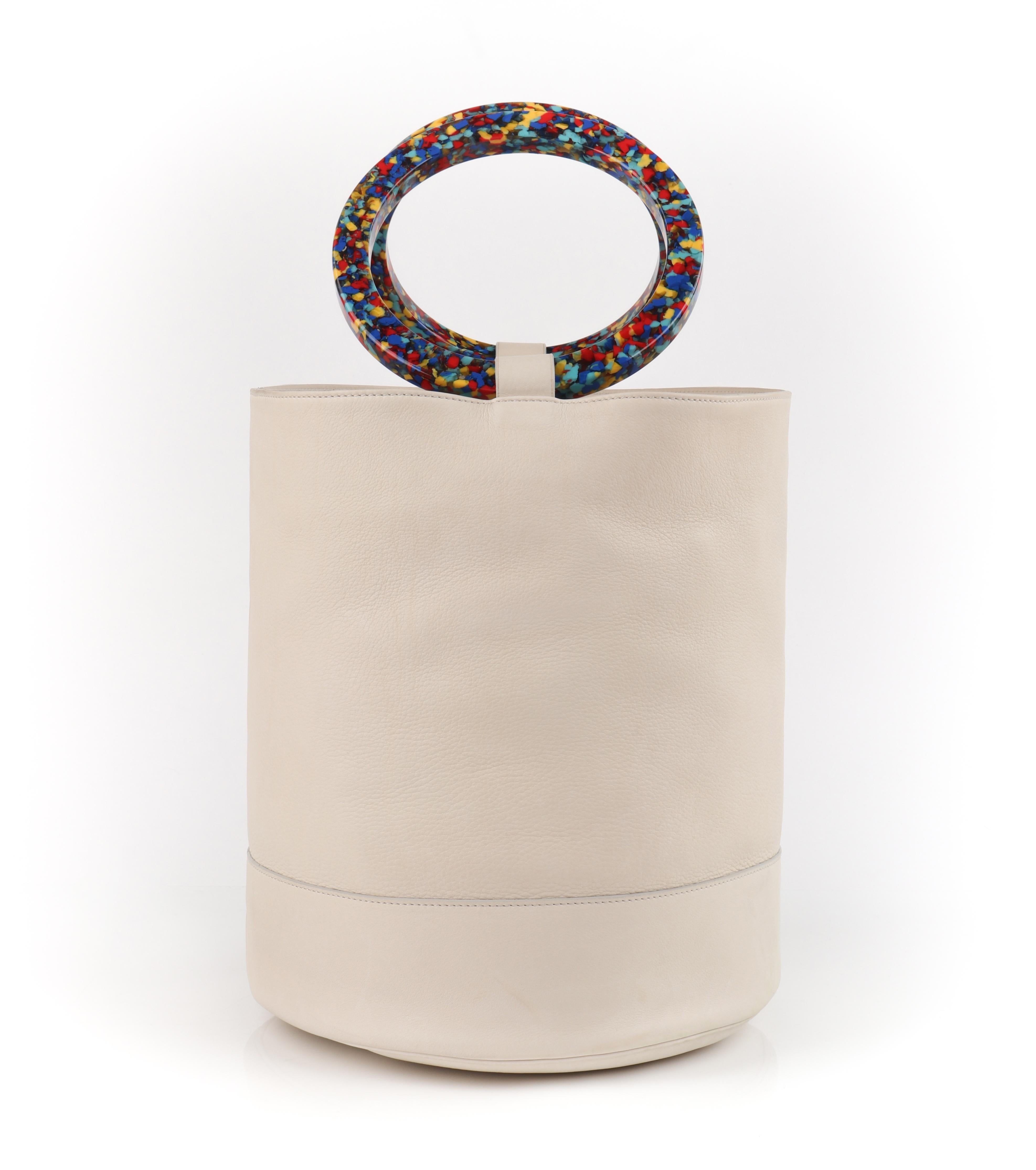 SIMON MILLER “Bonsai” 30 Off-White Multi-Color Ring Handle Nubuck Leather Bucket Handbag
 
Estimated Retail: $850
 
Brand / Manufacturer: Simon Miller
Manufacturer Style Name: Bonsai
Style: Handbag
Color(s): Shades of off-white, blue, yellow and