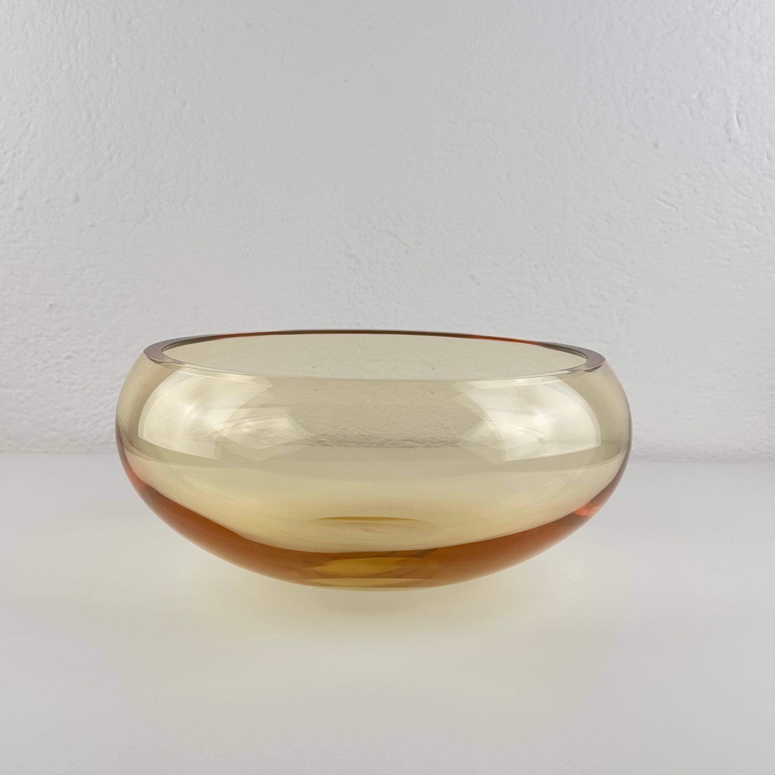 A striking hand-blown Murano glass centerpiece by Simone Cenedese, signed on the base, distinguished by its exceptional clarity and the rare chromatic nuance that shifts from transparent honey tones to a warm amber glow depending on the light. The