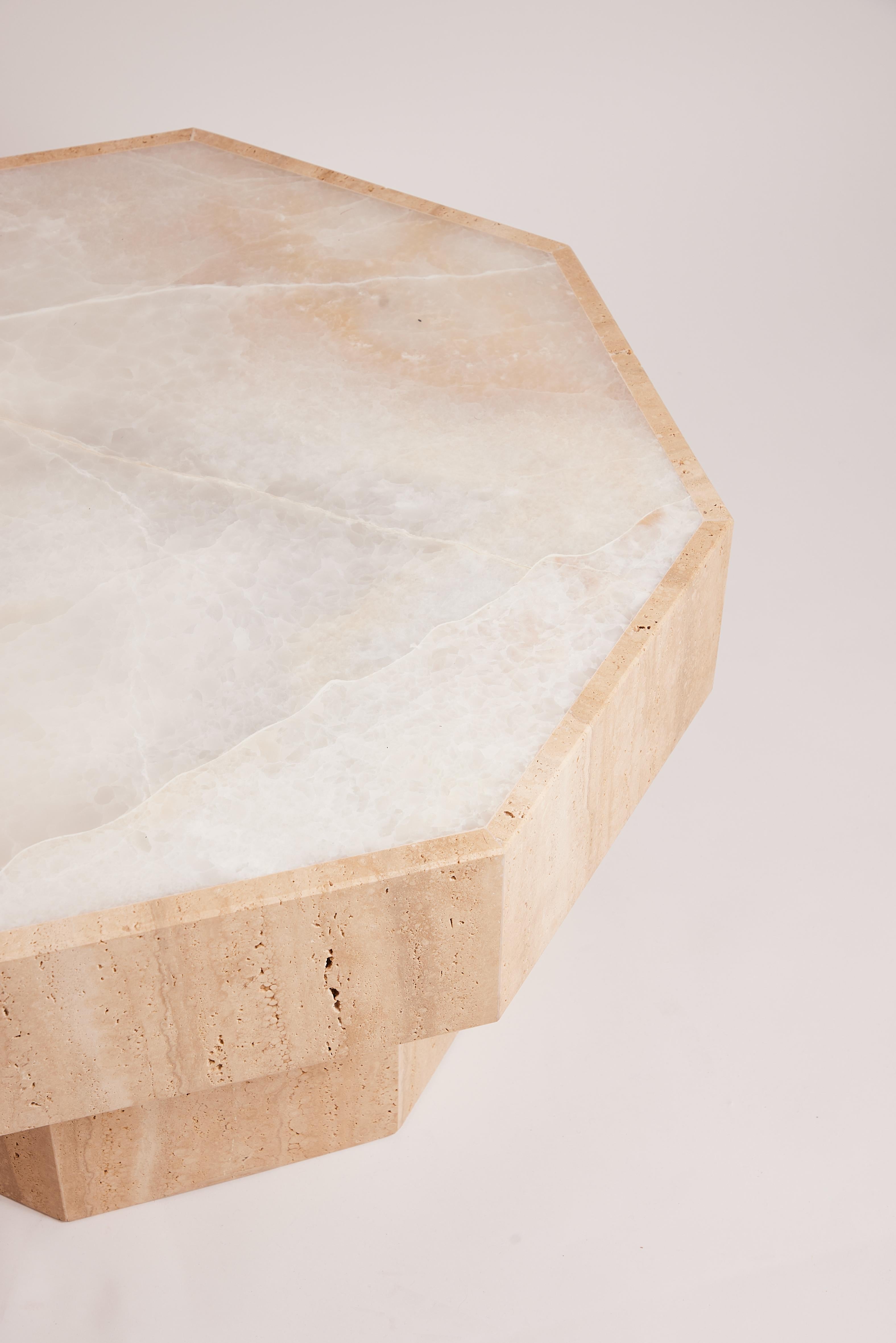 The Simone coffee table, in onyx and travertine, features two types of natural stones known for their unique beauty and durable properties. Onyx gives the table subtly translucent veins in hues from creamy white to golden honey, while travertine