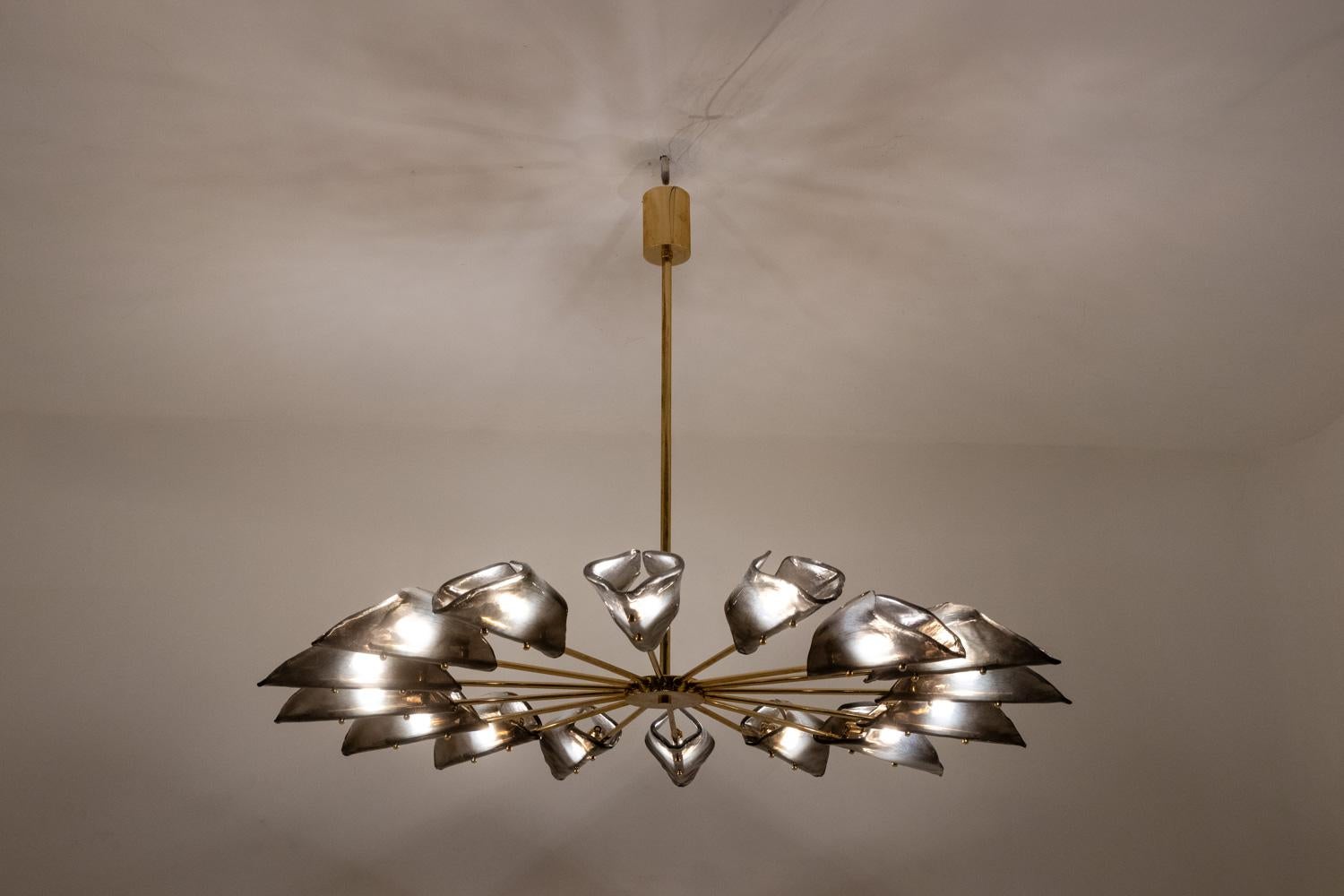 Simone Malachin, by.

Star-shaped chandelier with 16 arms of light, the frame in gilded and patinated brass, the Murano glasses in smoked color and triangular shape.

Work of contemporary Italian art craftsman.

Works with 16 G9 bulbs.

Dimensions: