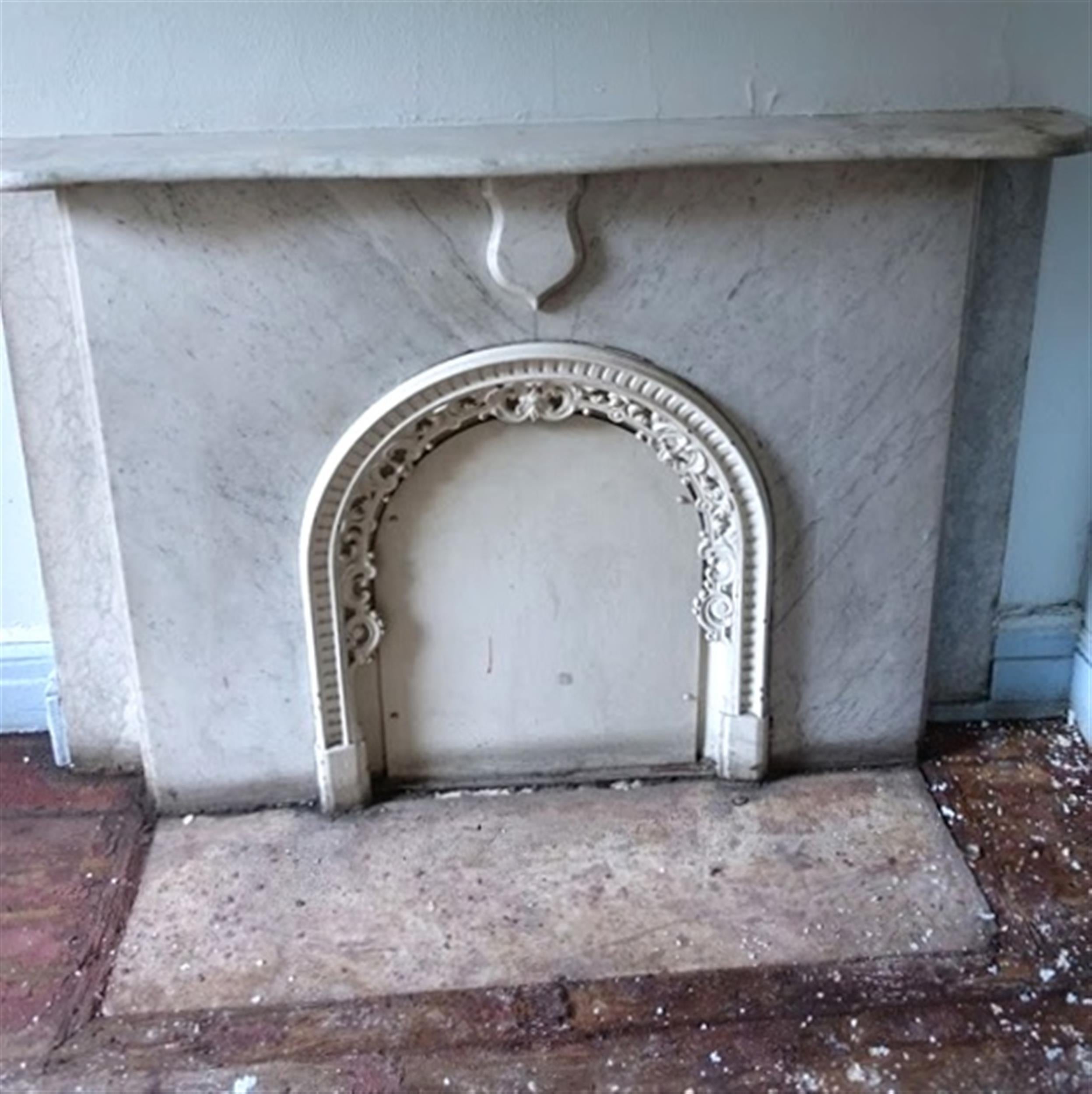 1900s white and gray veined carved Carrara marble mantel with flat face and flat shield keystone. It is pictured here in its original New York City brownstone home. This mantel comes with the ornate cast iron insert edge, but not the face of the