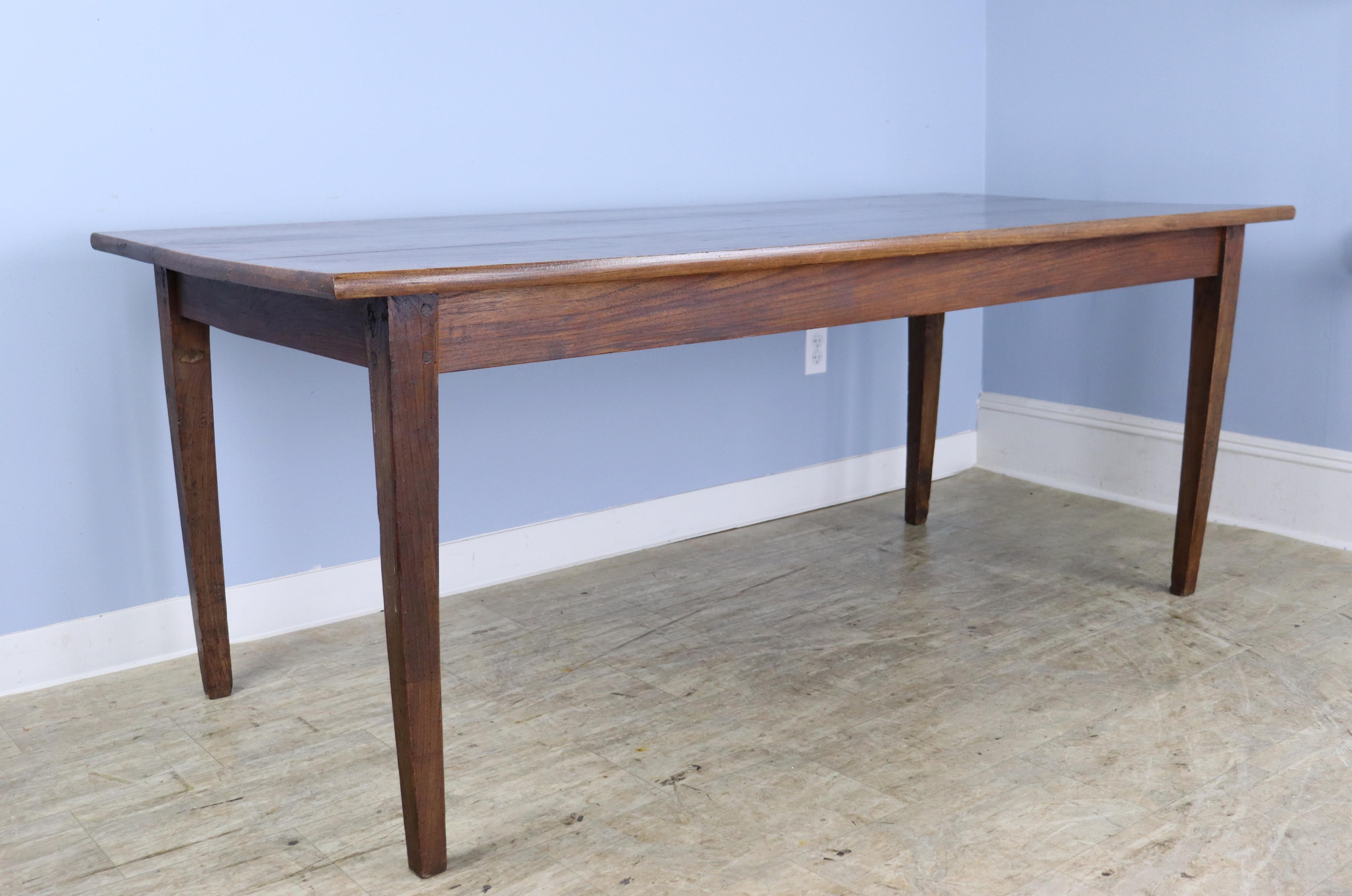 A simple elegant elm dining or farm table with wonderful elm grain and color.  The top is is in nice condition very little marks and wear.  The apron height of 24.5 inches is good for knees and there are 64.5 inches between the legs on the long side.