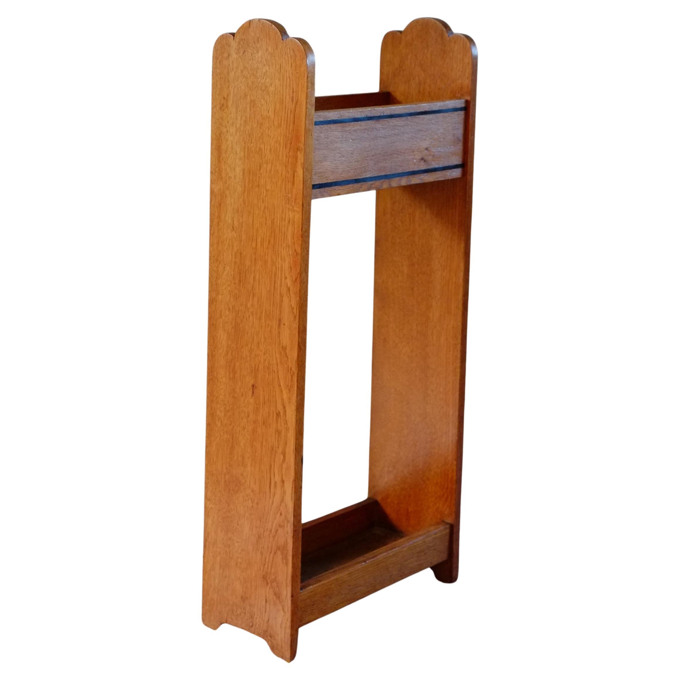 A really elegant and simple Arts and Crafts stick stand. This Arts and Crafts solid oak stand has a lovely cloud shape at the top and the simplest shaped feet. Beautiful honey oak colour with two ebonised, fine line inlay details across the front.