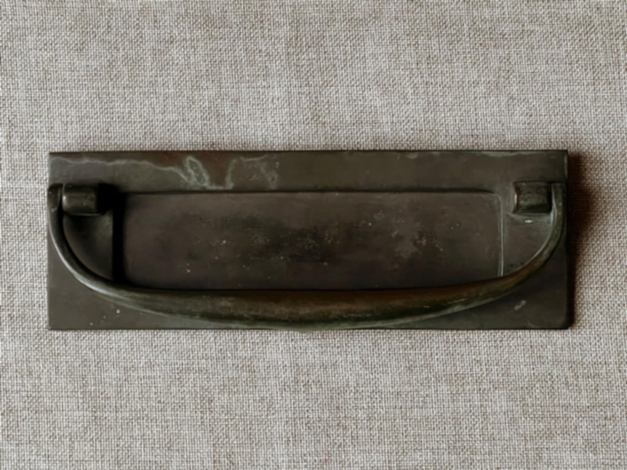 Una sencilla tapa de buzón con solapa accionada por resorte, que incorpora tirador de puerta / aldaba. Estilo art nouveau, primera mitad del siglo XX. Encontrado en Inglaterra.

La pieza es de bronce macizo con una hermosa pátina oscura, que hemos