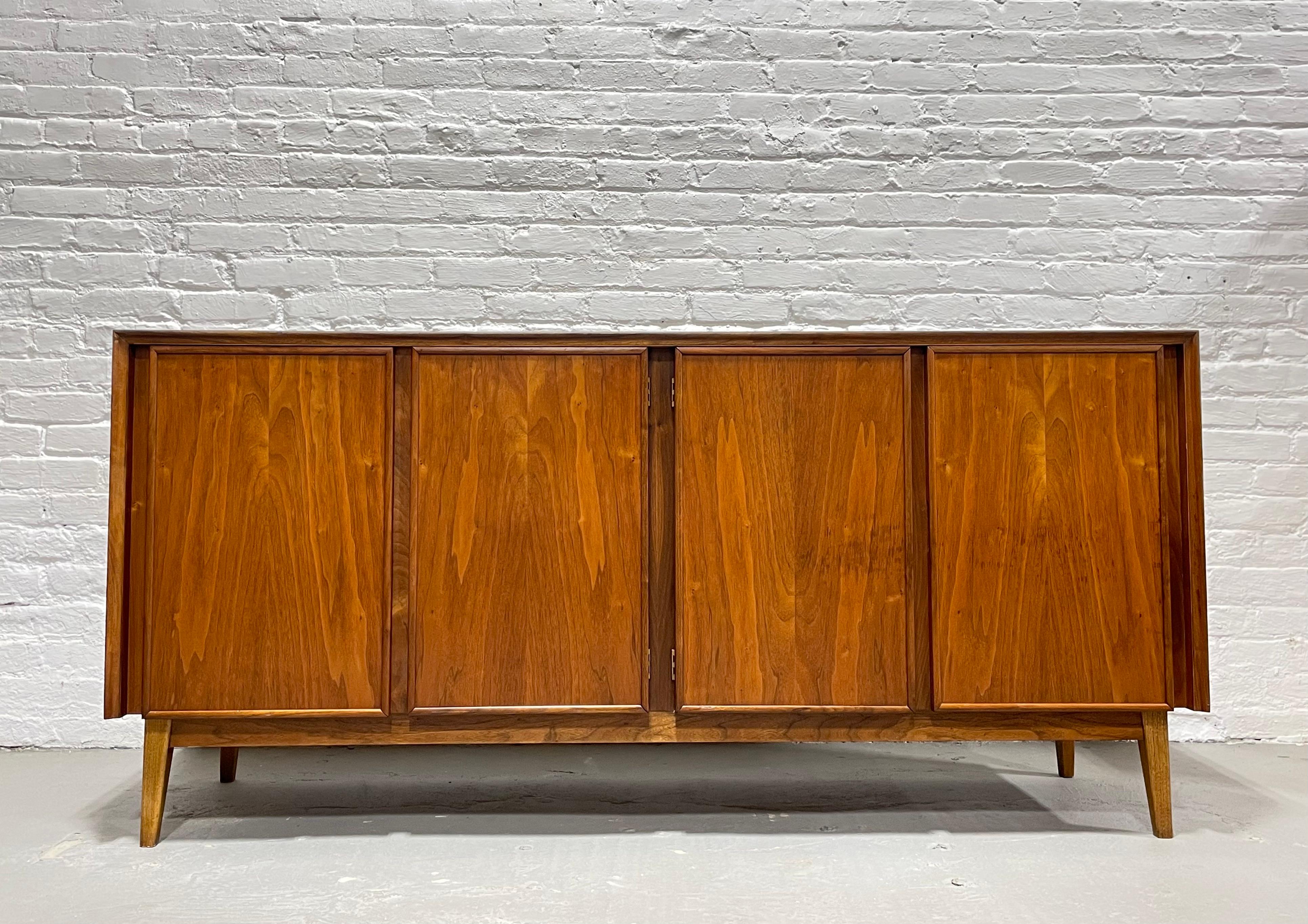 Simple + perfect Mid-Century Modern walnut Credenza / Media stand designed by Merton Gershun for American of Martinsville. This classic credenza features a simple front panel design and is constructed of walnut with the most gorgeous wood grains.