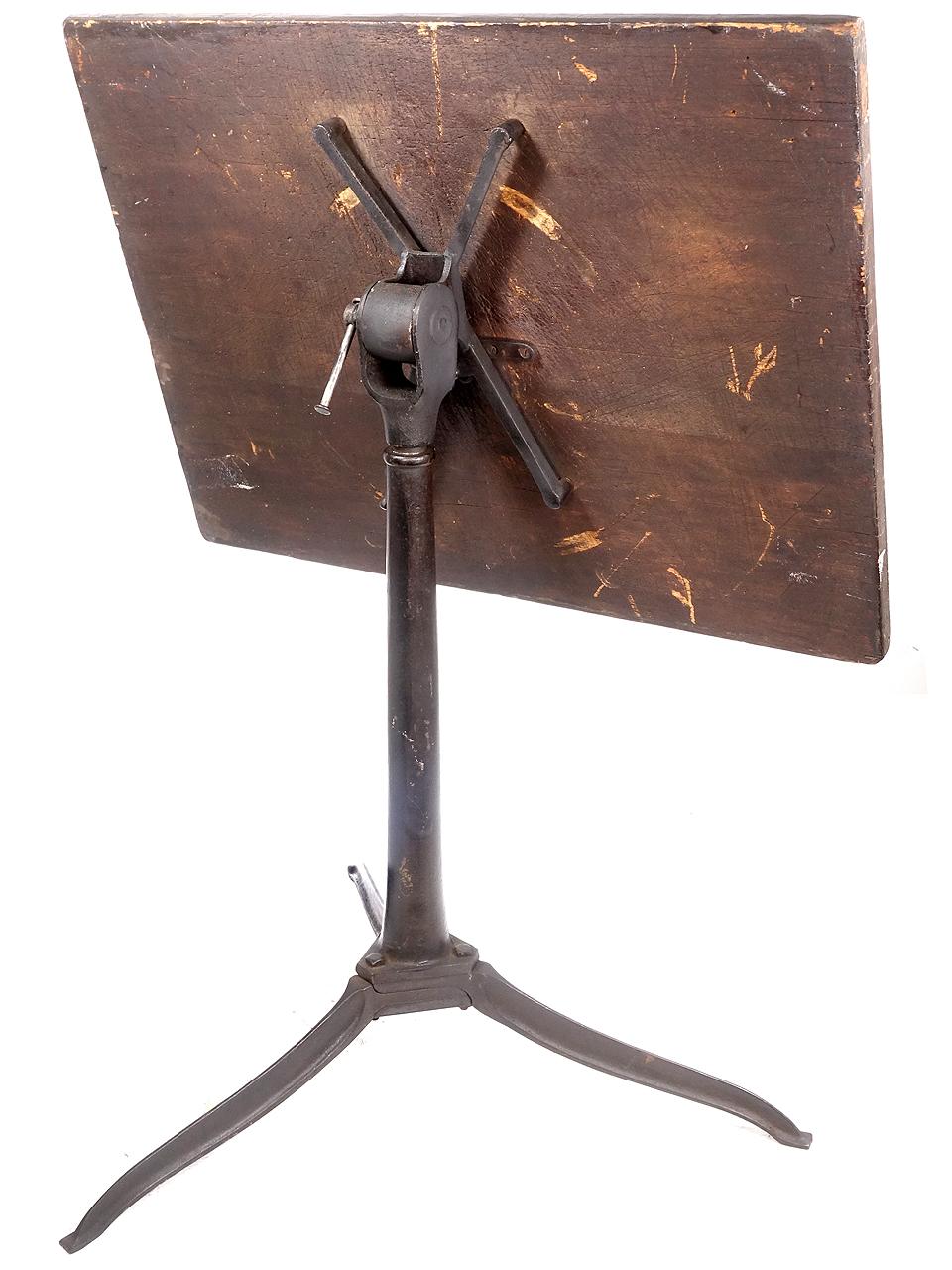 This 1920s drafting or art table is untouched. The finish on the wood and iron base is all original. It has an aged patina that is just right. The wood top is only 23 x 31 inches and is small enough to be used as a unique display stand. It will tilt