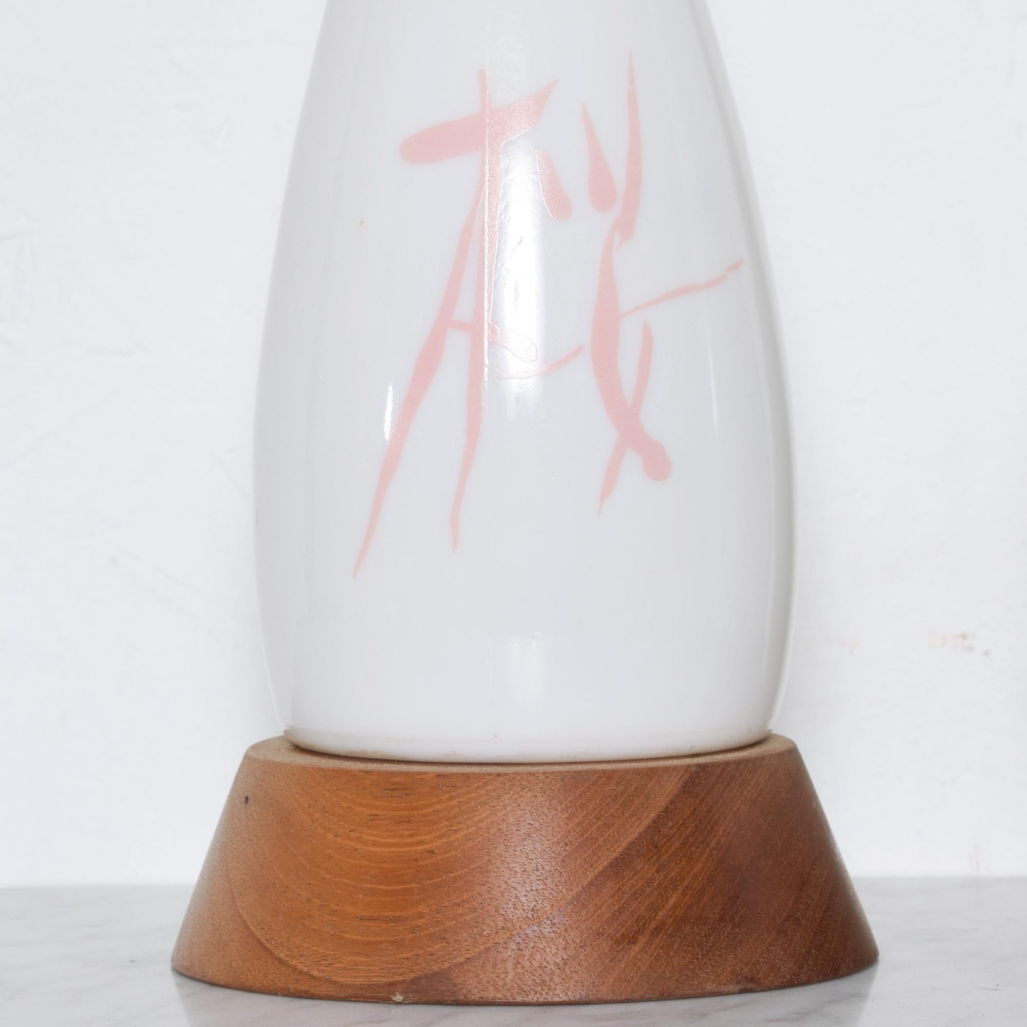 Set of two modernist lamps in creamy milk glass Asian motif table lamps mounted on a modern wood base.
No additional maker information is available.
Features Chinese symbol writing on design
Dimensions: 16 tall x 5 inches in diameter