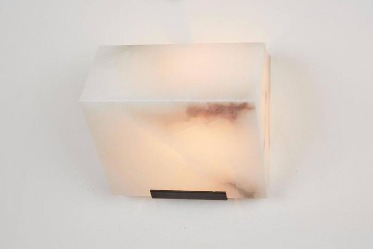 Originally designed in 1923 this current production by Galerie MCDE of France of the simple sloping wall lamp by Pierre Chareau is composed of a single block of alabaster. This wall lamp is also available in double or triple blocks. Hue of alabaster
