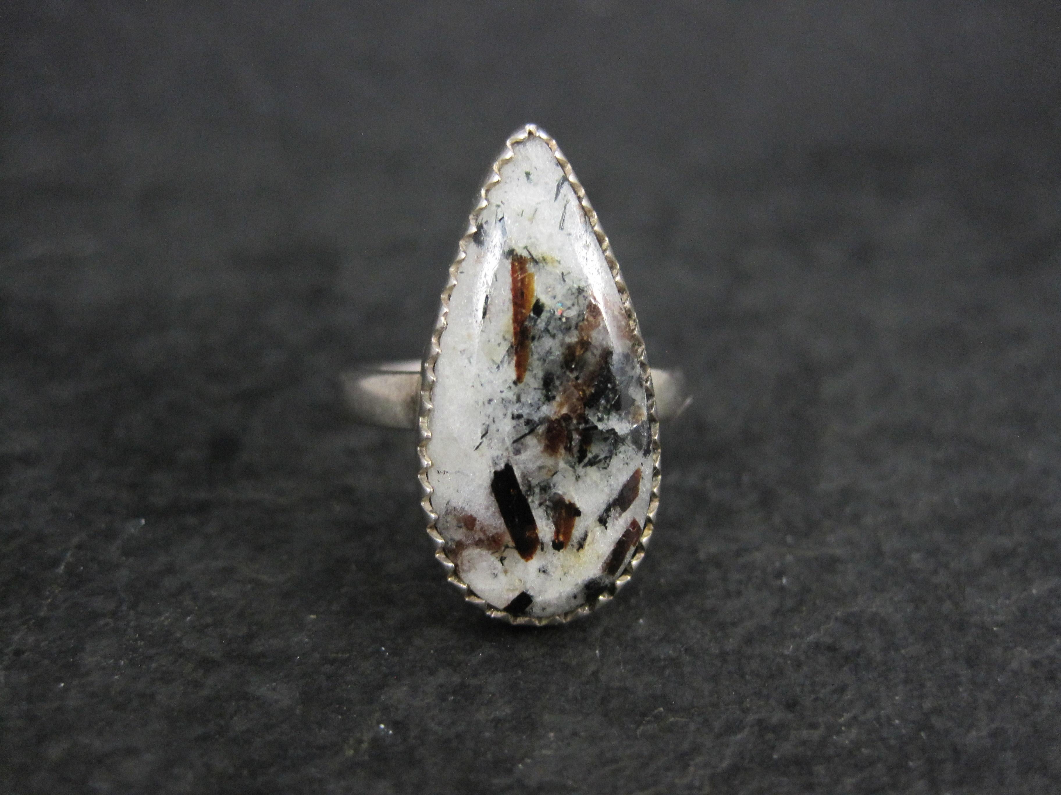 Cette magnifique bague de style sud-ouest est en argent sterling.
Elle est ornée d'une astrophylite de 11x23 mm taillée en poire.
La face de cette bague mesure 1 pouce du nord au sud.
Taille : 8
Condit : Excellent