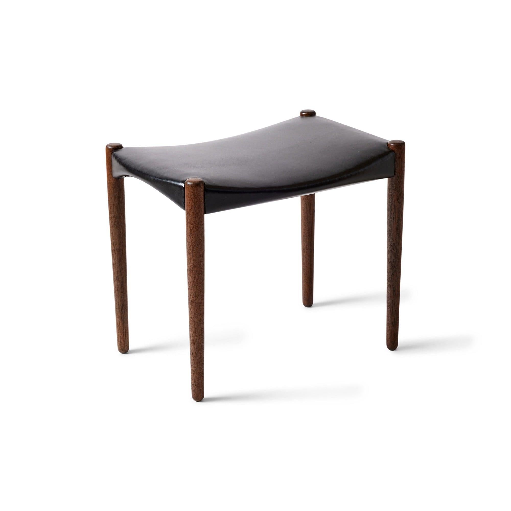 Uno sgabello di lusso e ben realizzato con una seduta in pelle nera che poggia su gambe affusolate in legno di teak.