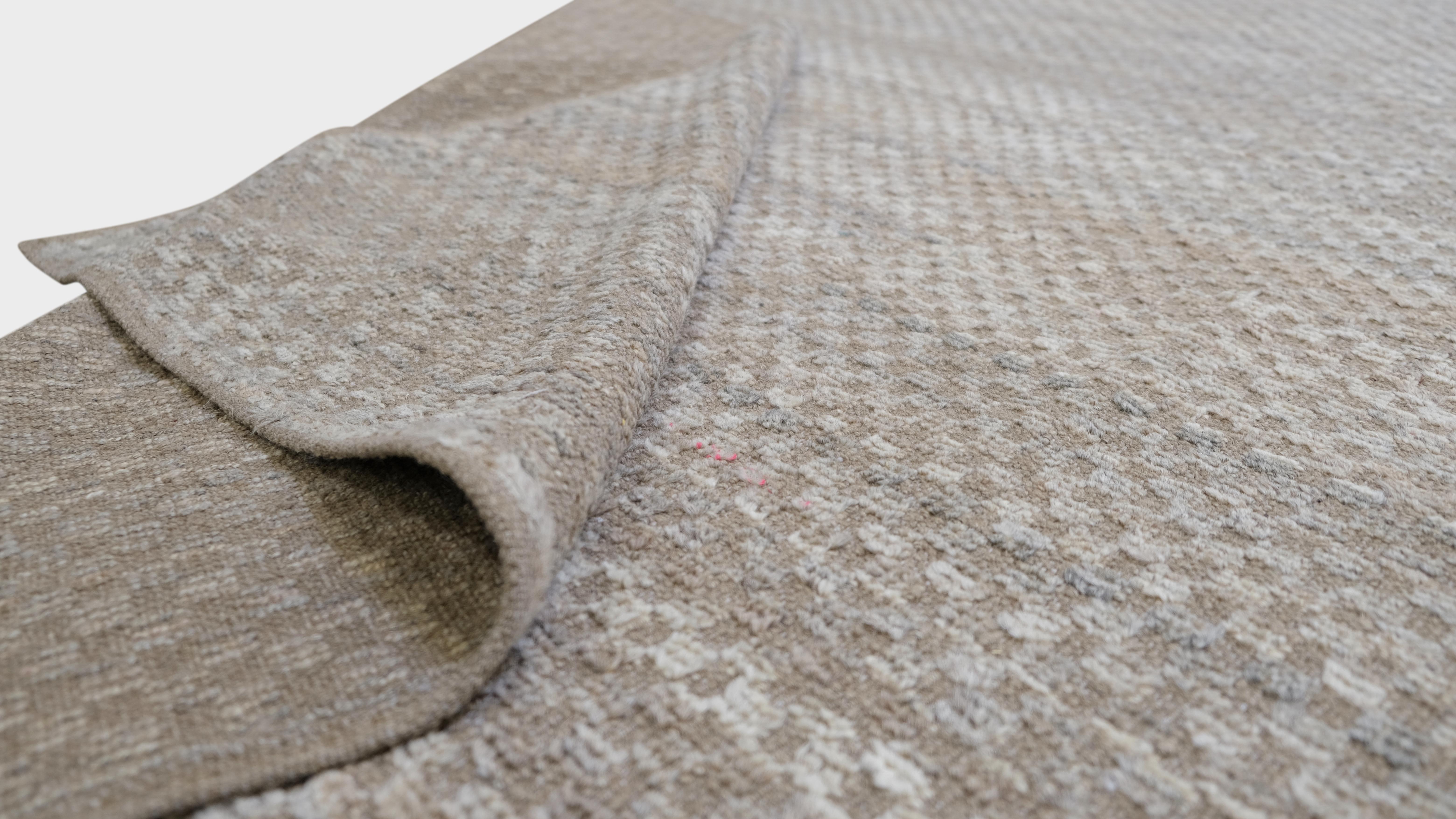 Discover the understated elegance of this hand-knotted wool rug, showcasing a minimalist textured design in versatile neutral tones. This exquisite piece seamlessly blends timeless craftsmanship with modern aesthetics, making it the perfect