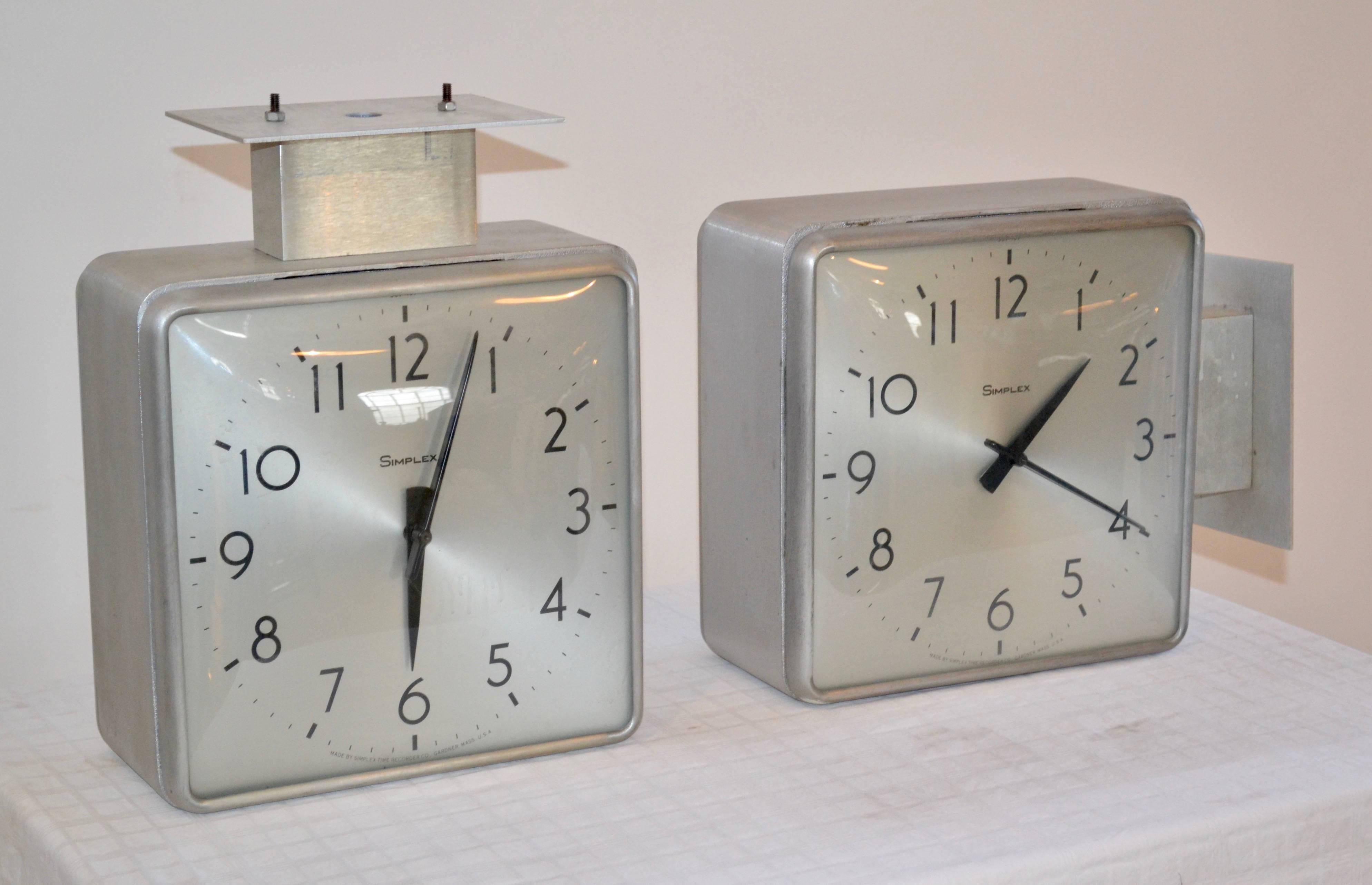 These Simplex double-sided clocks have cast aluminium housings. Clips are present that allow for different mounting configurations. They can also be completely detached from the housing if hanging straight on the wall is preferred. Time adjustments