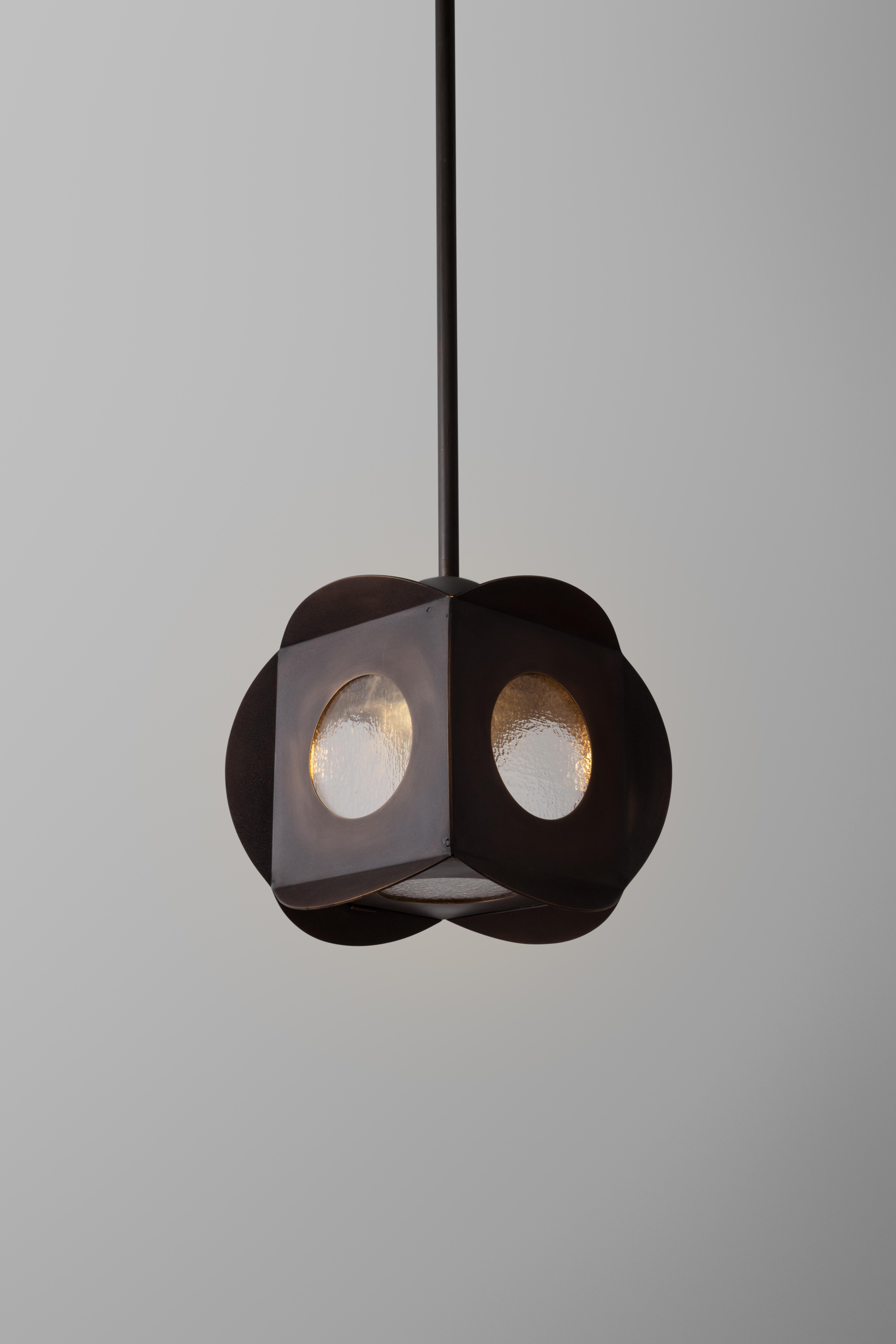 Cubic pendant made by intersecting brass circles. The bottom of the fixture is a latched door entry. 
Circular windows invite the viewer to peek into the fixture.

The fixture is sandblasted to give it a natural aged beach-worn appearance, and