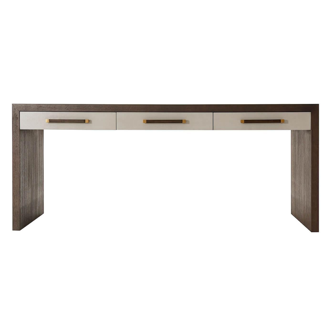 An elegant modern writing table with three singular leather wrapped drawers, our Cardamon finish on the veneered frame (and handles) with panel end supports and brushed brass finish accents.

Dimensions: 72