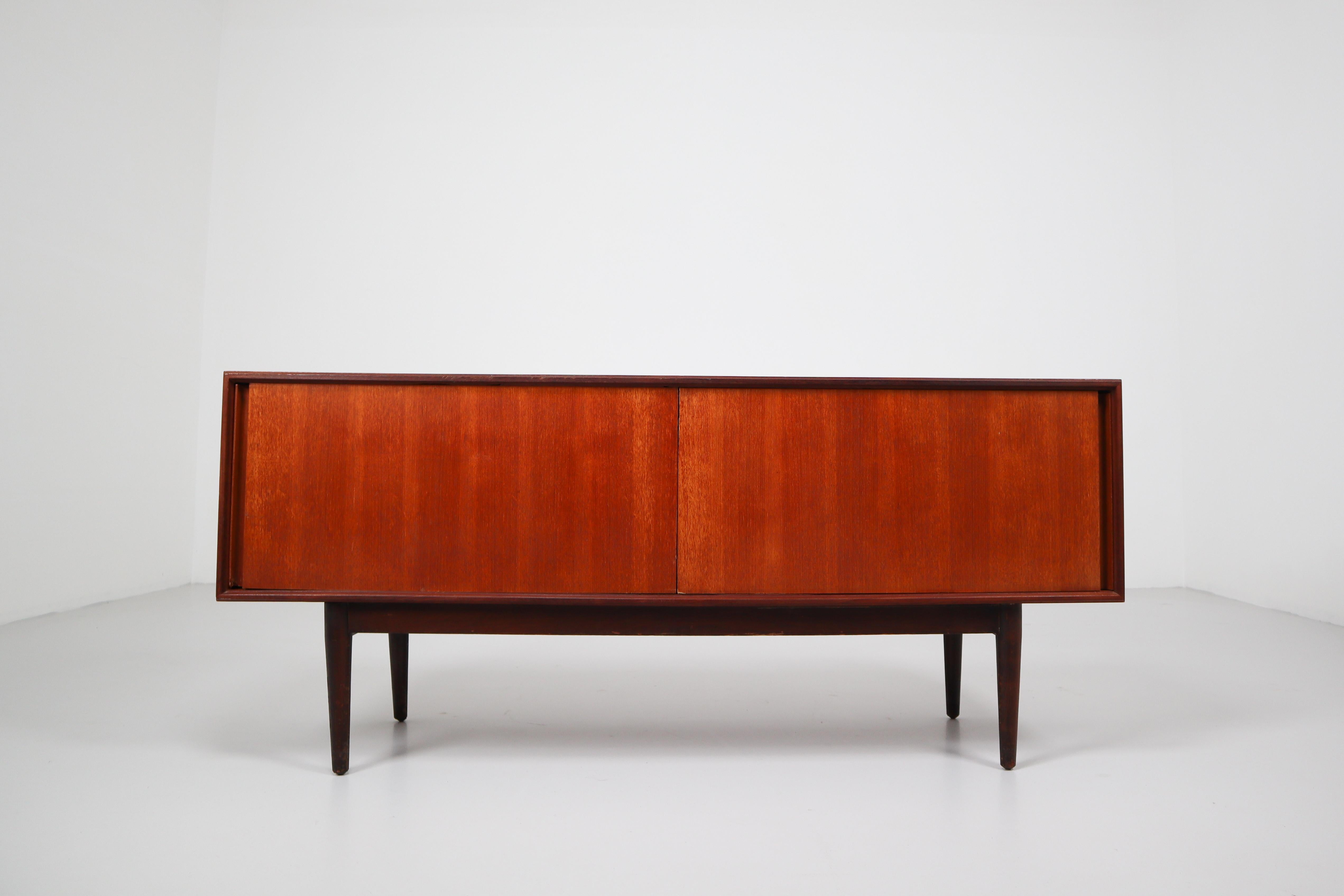 Simply teak sideboard from the 1960s Made in Denmark in a smooth design where the beautiful wood grain falls into focus on the two sliding doors. Preserved in good condition and original patina (small bruises and scratches) - directly for use. 
