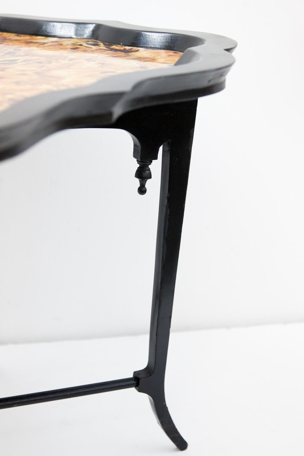 Simulated tortoise shell table has a cross stretcher base. The inlaid simulated tortoise shell is set in book matched format with scalloped border. There is an inlaid brass center cartouche.