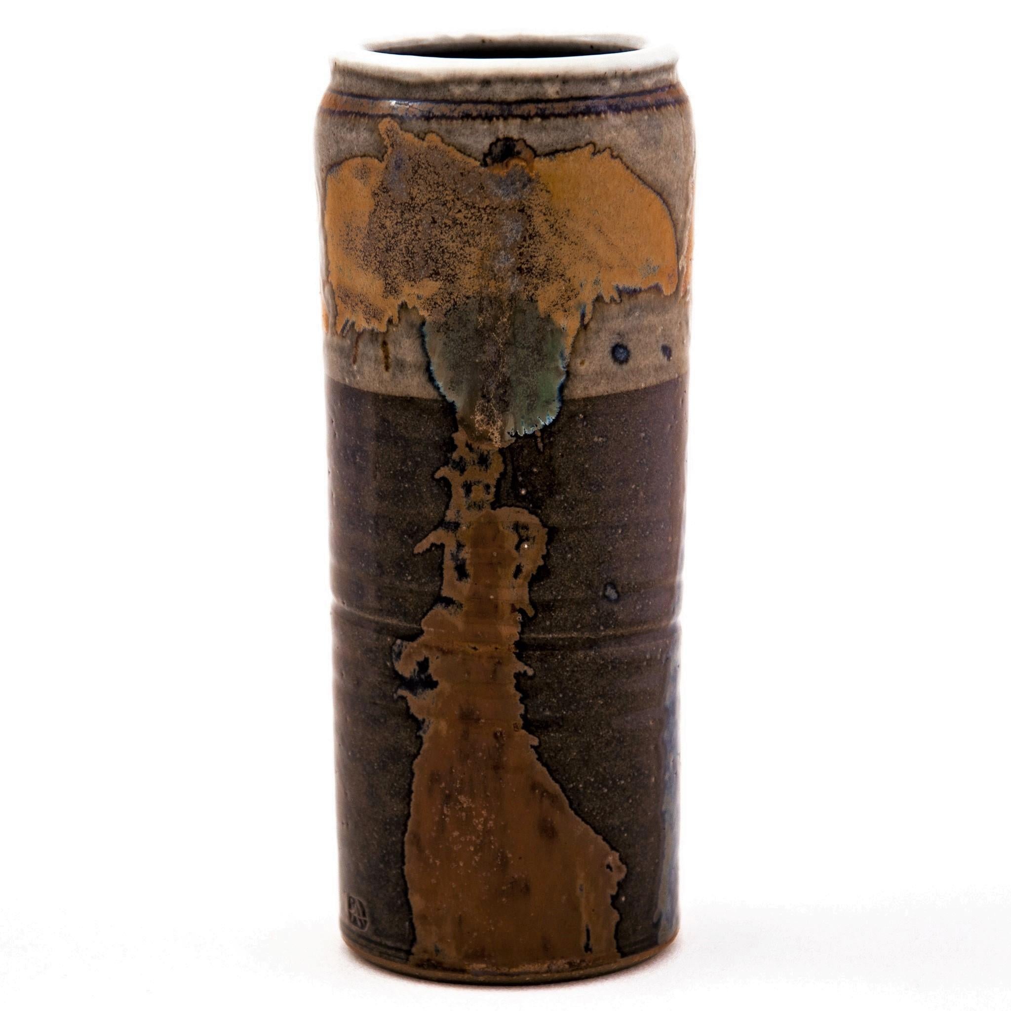 Vintage cylindrical thrown stoneware vase depicting three abstract trees glazed with deep earth tones by Sinclair W. Ashley (1942-1997). The glaze colors include dark brown, burnt orange and moss green with a light gray rim and interior. It is