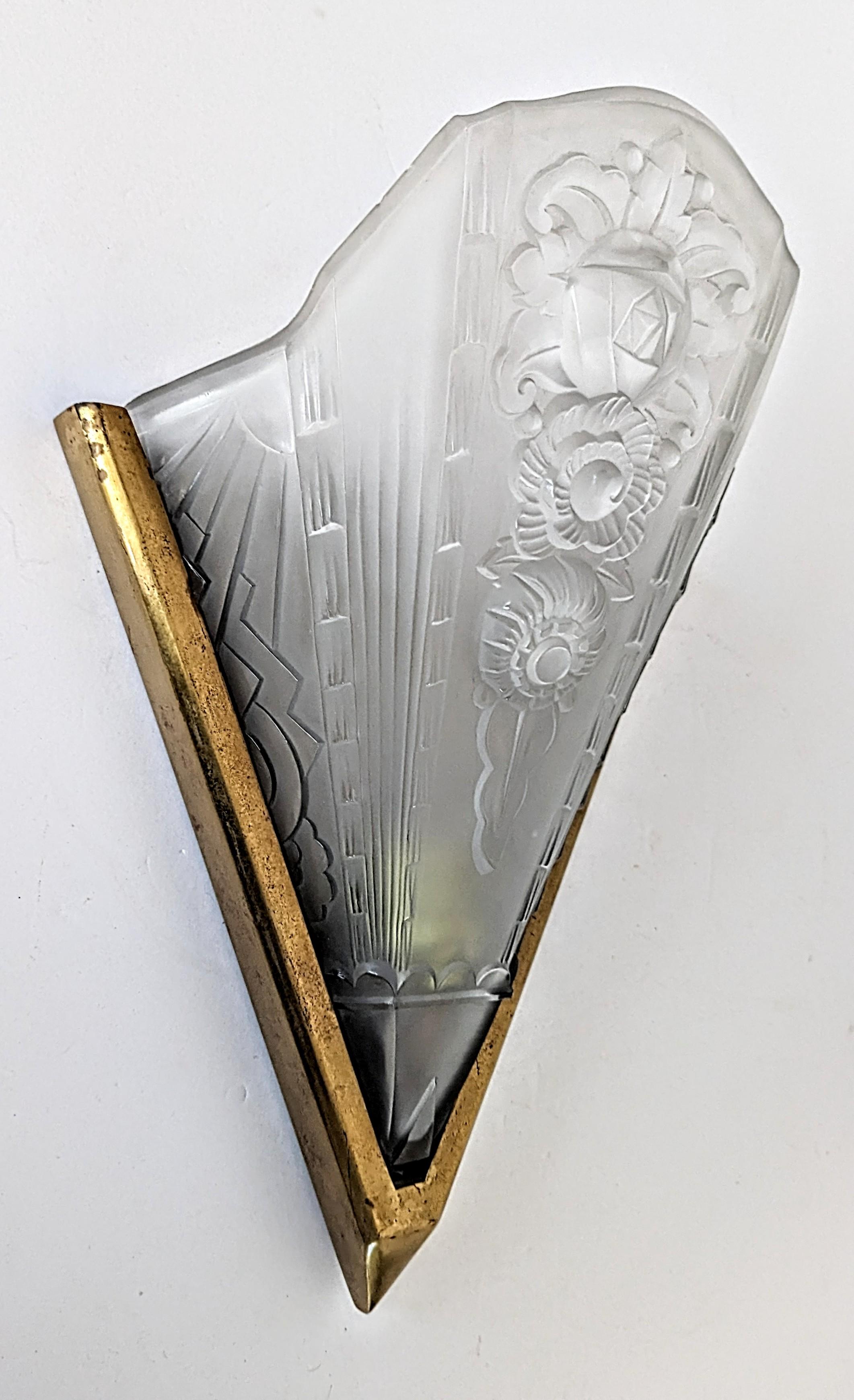 A single French Art Deco wall sconce in good condition. Molded clear frosted glass shade decorated with geometric and floral motifs. Mounted in a golden frame. The sconce has been rewired for U.S. standards. Accommodates a household bulb E-26