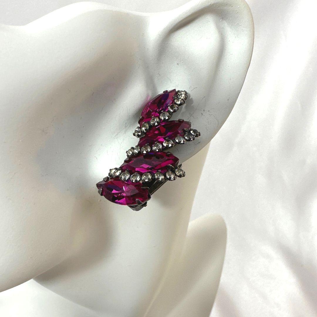 Immerse yourself in the timeless elegance of the Signed Weiss Vintage Burgundy Purple Rhinestone Clip-On Earrings, a captivating piece of fashion jewelry that effortlessly combines vintage charm with contemporary style.

Crafted by the renowned