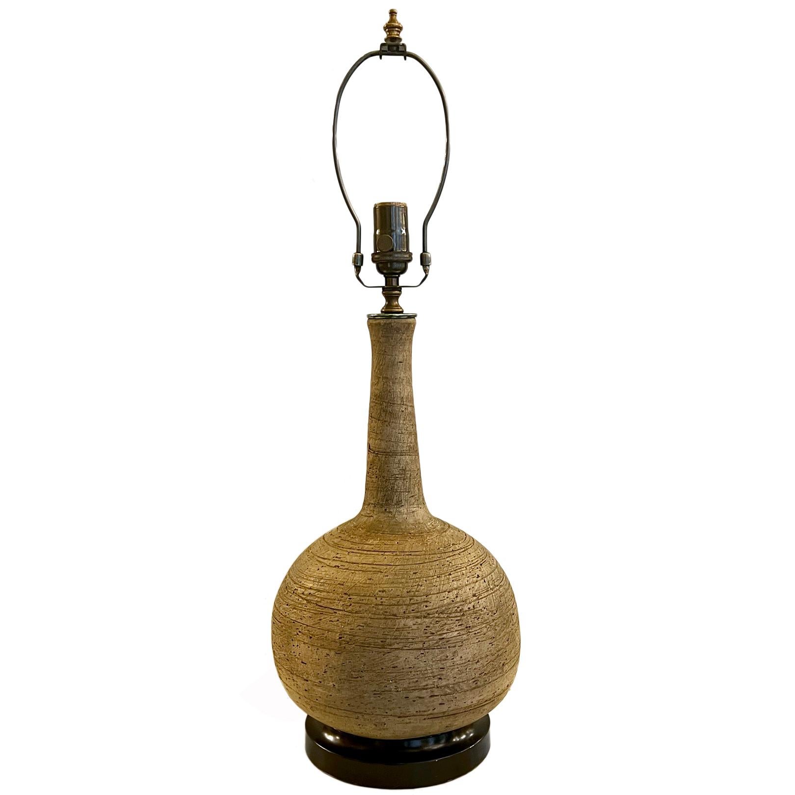 A circa 1950's Italian unglazed ceramic midcentury table lamp with wood base.

Measurements:
Height of body: 17