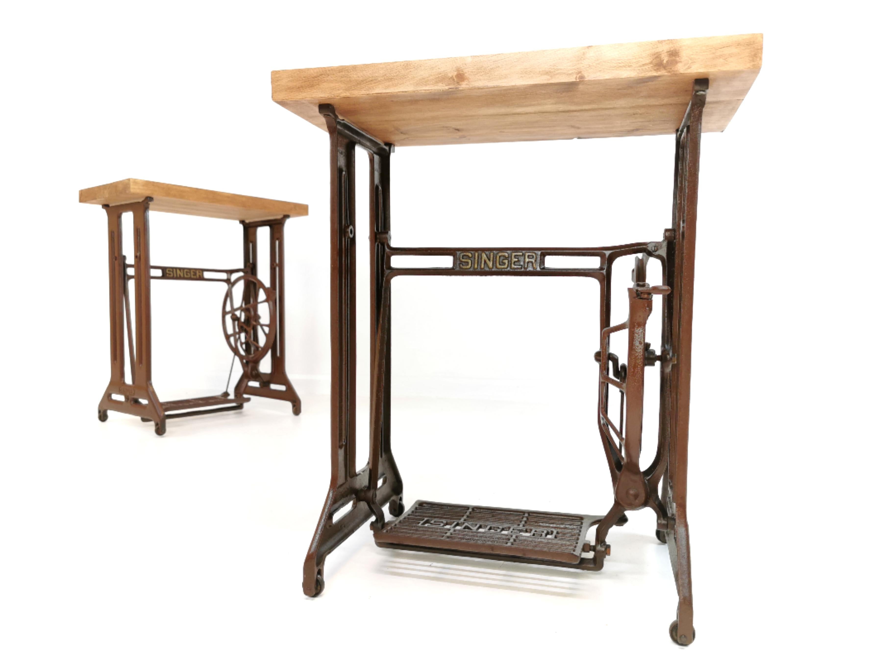 Two original singer sewing machine treadle stands fitted with a reclaimed wooden top.

These stands were originally made in Singers Kilbowie factory, Clydebank Scotland. The brown stands are not found as often.

Superb industrial Art Deco lines.
