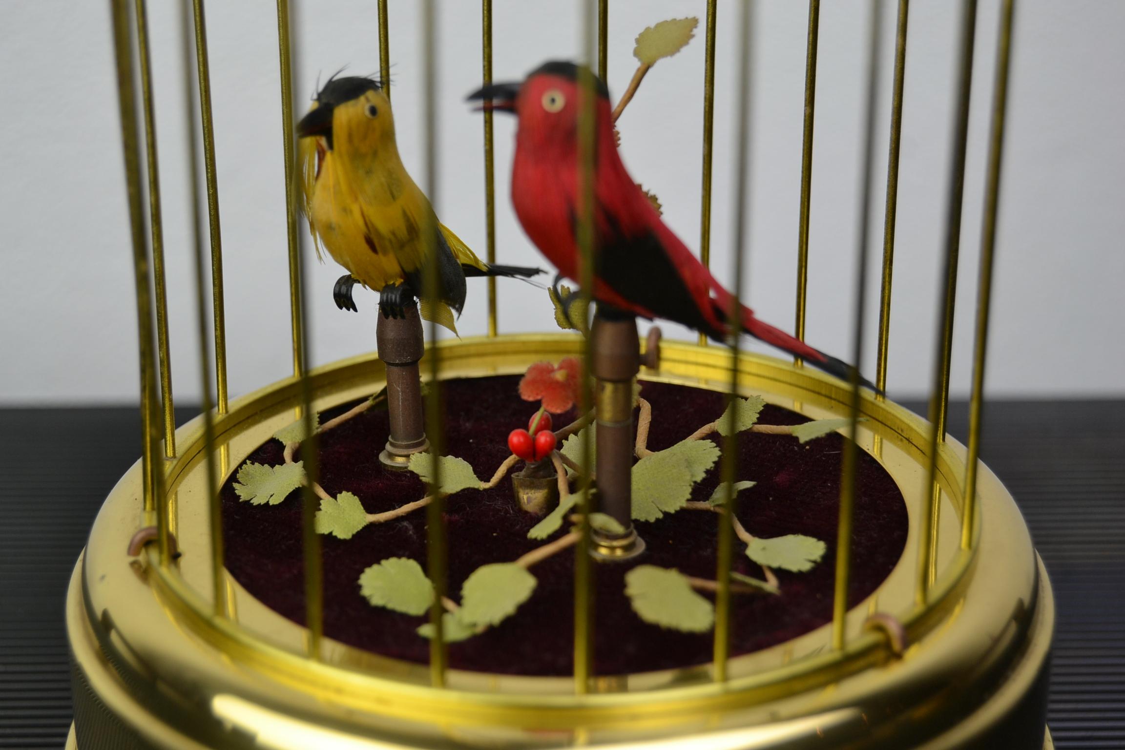 Mechanical birdcage with two singing birds inside.
This automaton has a red and yellow singing bird in the cage. 
As well the birds as the plants are very fine detailed. 

The birds in this singing bird music box have realistic sound of real