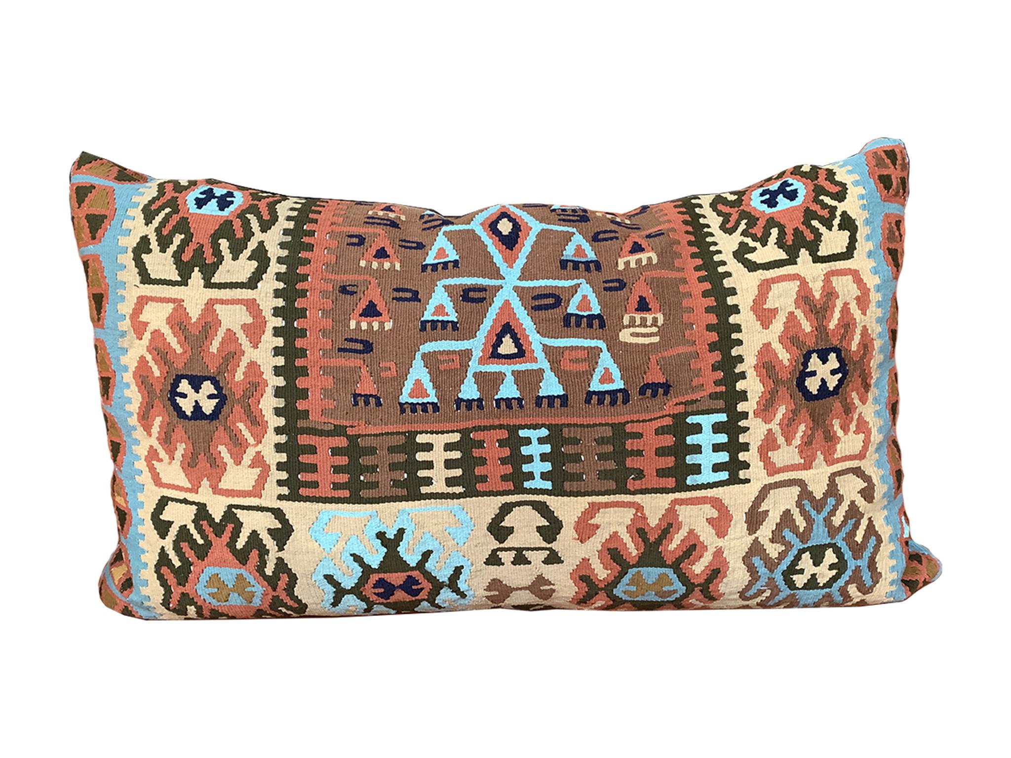 Questo cuscino singolo è stato realizzato su misura a partire da una coperta di lana Navajo del XIX secolo. Il tessuto è intrecciato a mano in un intricato disegno geometrico, con una ricca tavolozza di blu chiaro, rosso chiaro, marrone, arancione