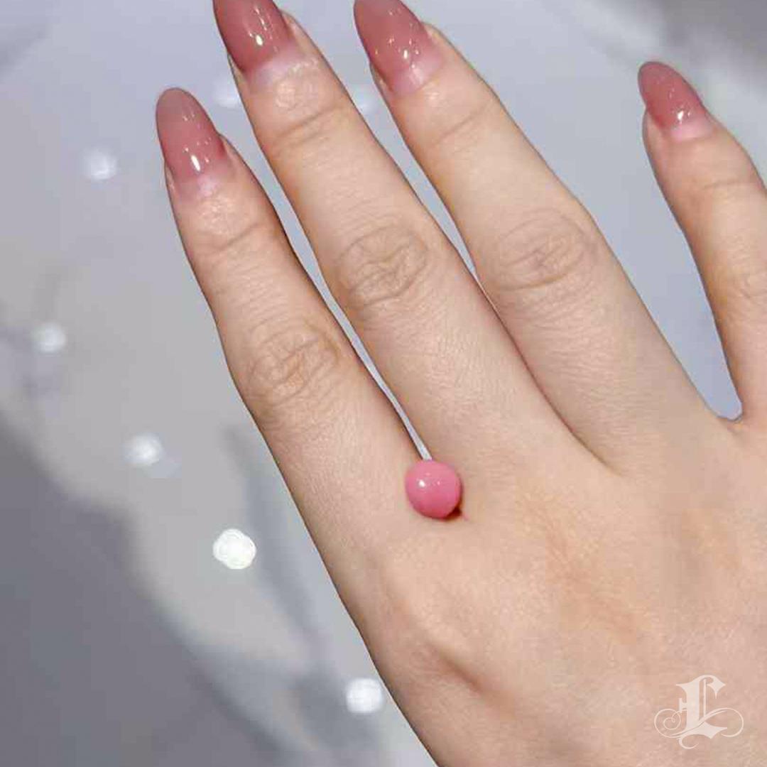 A rare find among conch pearls, this 2.60-carat natural gem exhibits the most coveted combination: a nearly perfect round shape, an intense flamingo pink hue, and a strong, well-defined flame pattern.
Its compact yet full-bodied form makes it ideal