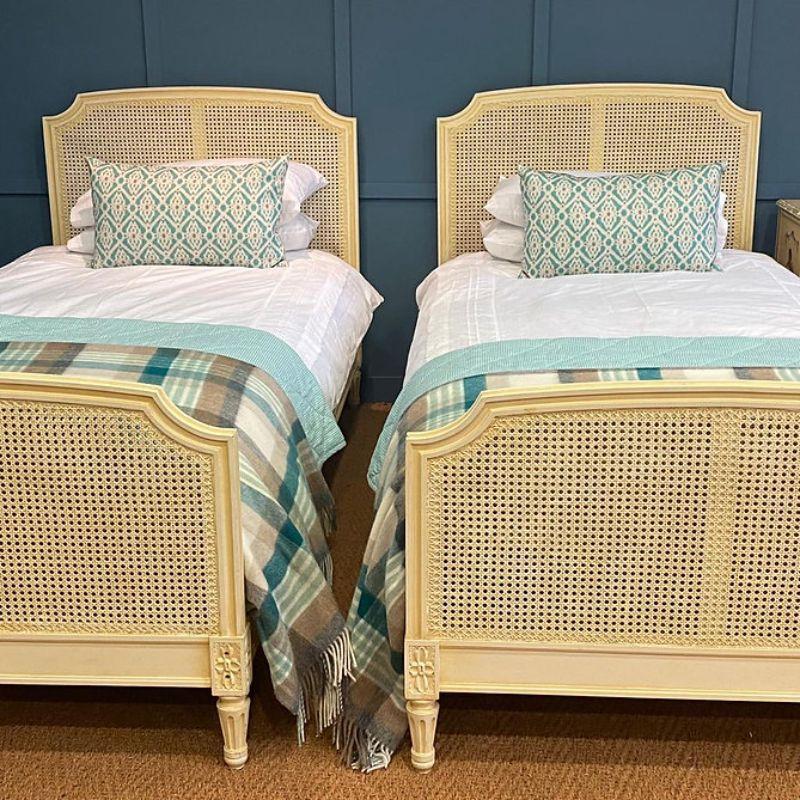 A matching pair of 3’ wide pretty single caned beds which are painted in a pale cream colour with a colour wash onto of the frame.

The cane is in excellent condition and the beds come complete with superior new firm bed bases. This pair of beds