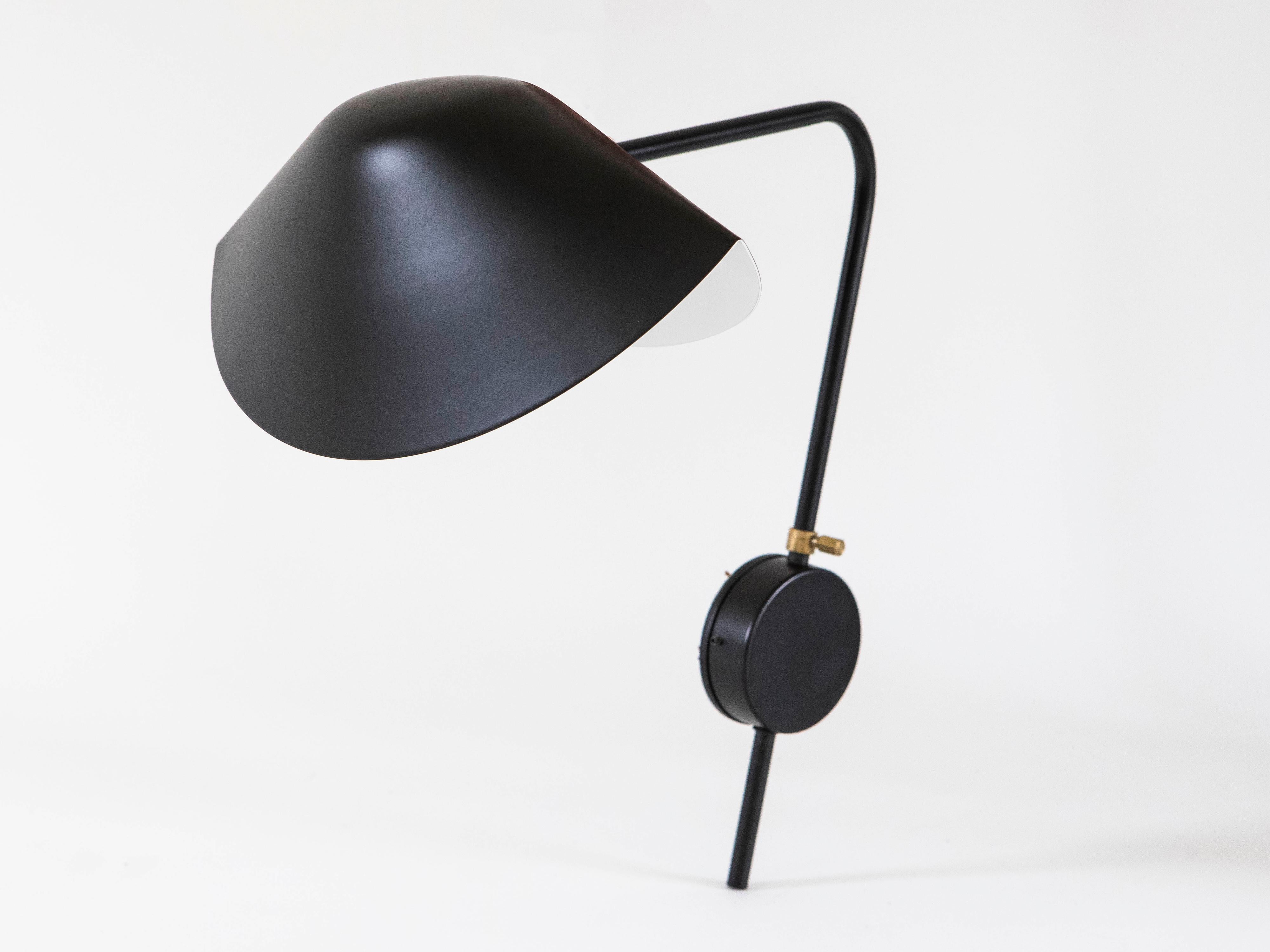 Serge Mouille single arm black Antony sconce, 2013 edition by Gueridon. The mussel-shaped shade is connected by a brass swivel and supported on a bent, rotating arm attached to the wall by a round mounting bracket. 1 socket, 60 W max.
