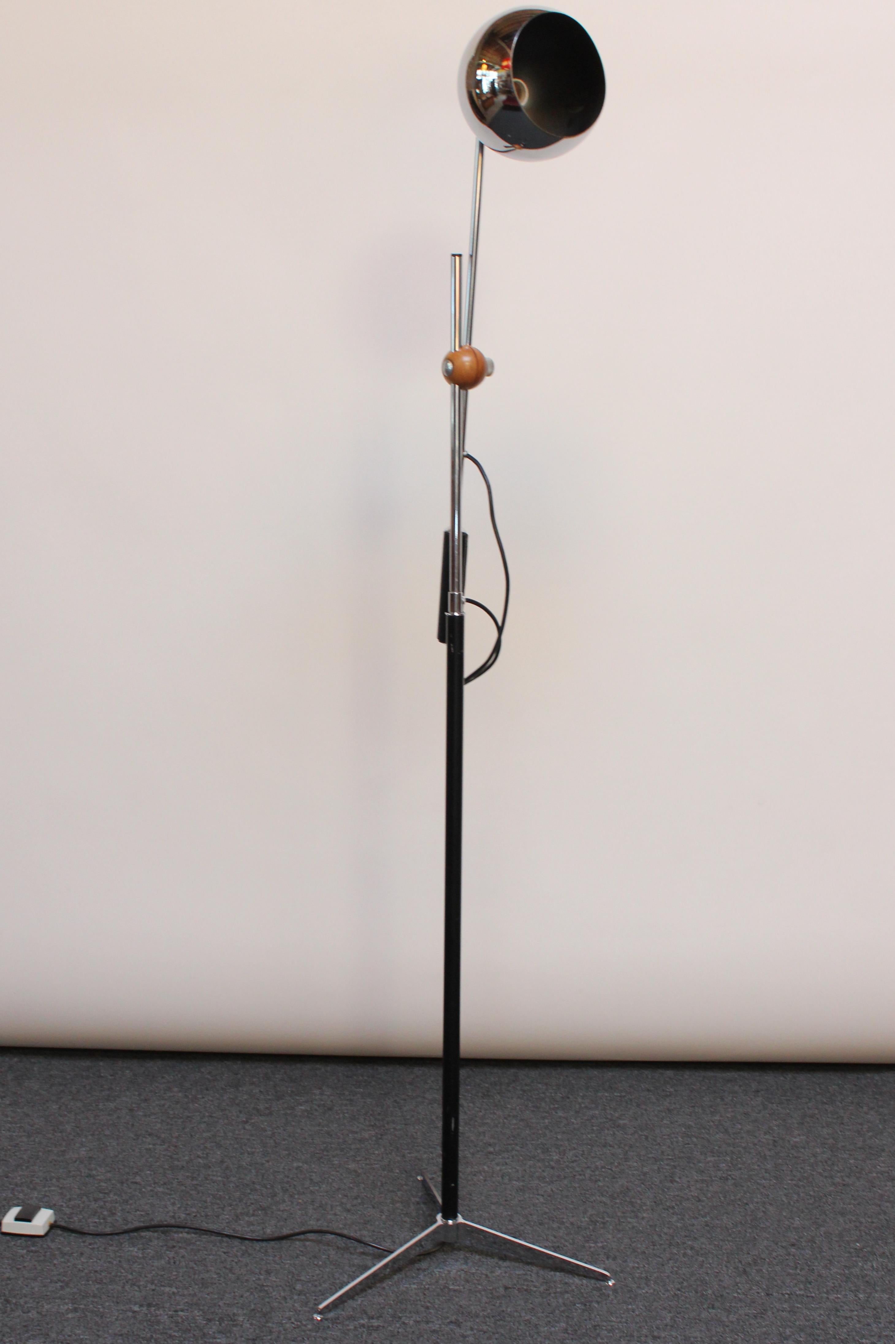 Chrome floor lamp manufactured in the 1960s by Arteluce. 
Composed of a single, counterbalanced arm with an adjustable globe shade and leather wrapped handle, all supported by a black enameled shaft and tripod base. 
The plastic clasp has been