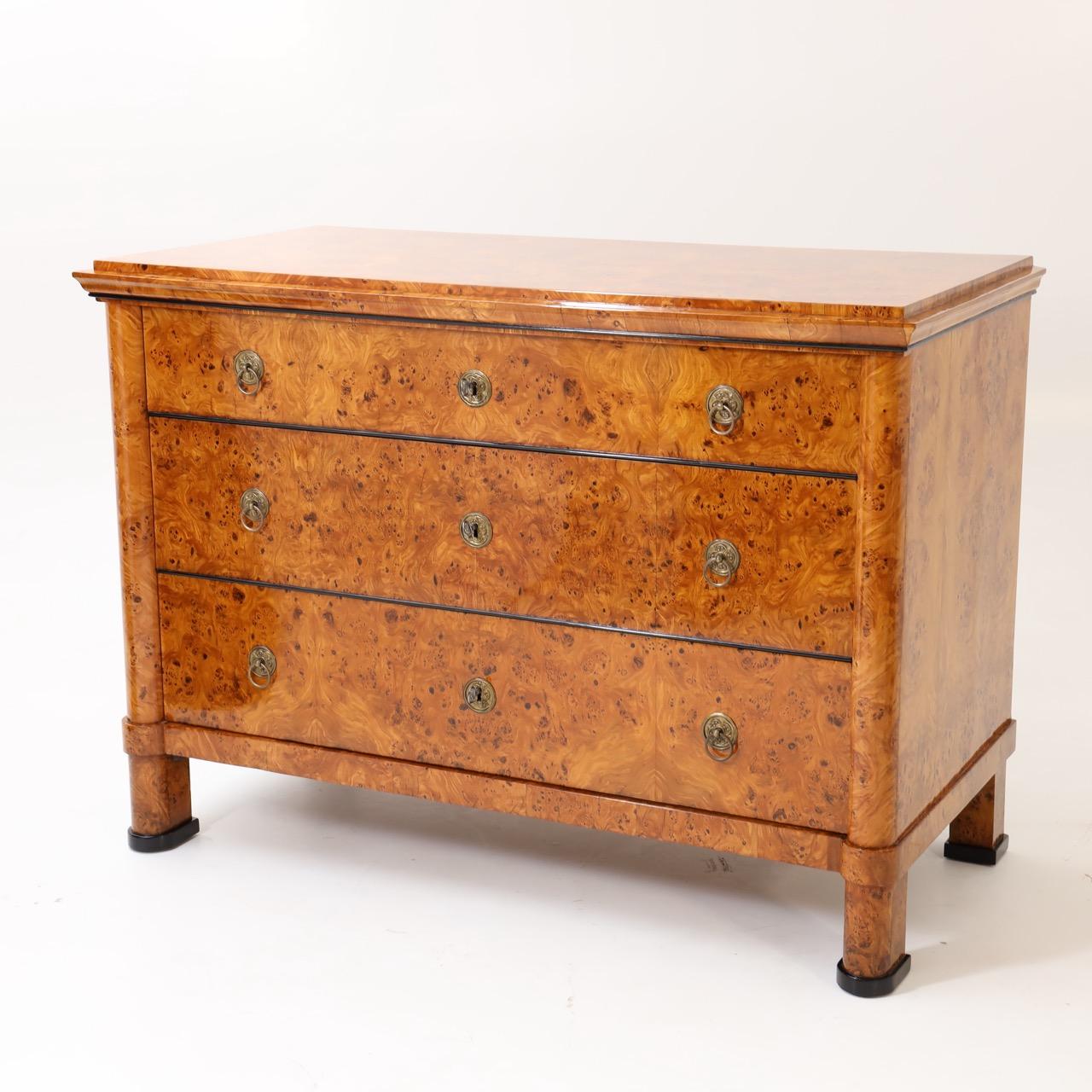 A fine Biedermeier three drawer chest. 
Poplar Burl with patinated brass pulls and escutcheons
and ebonized fruitwood feet.