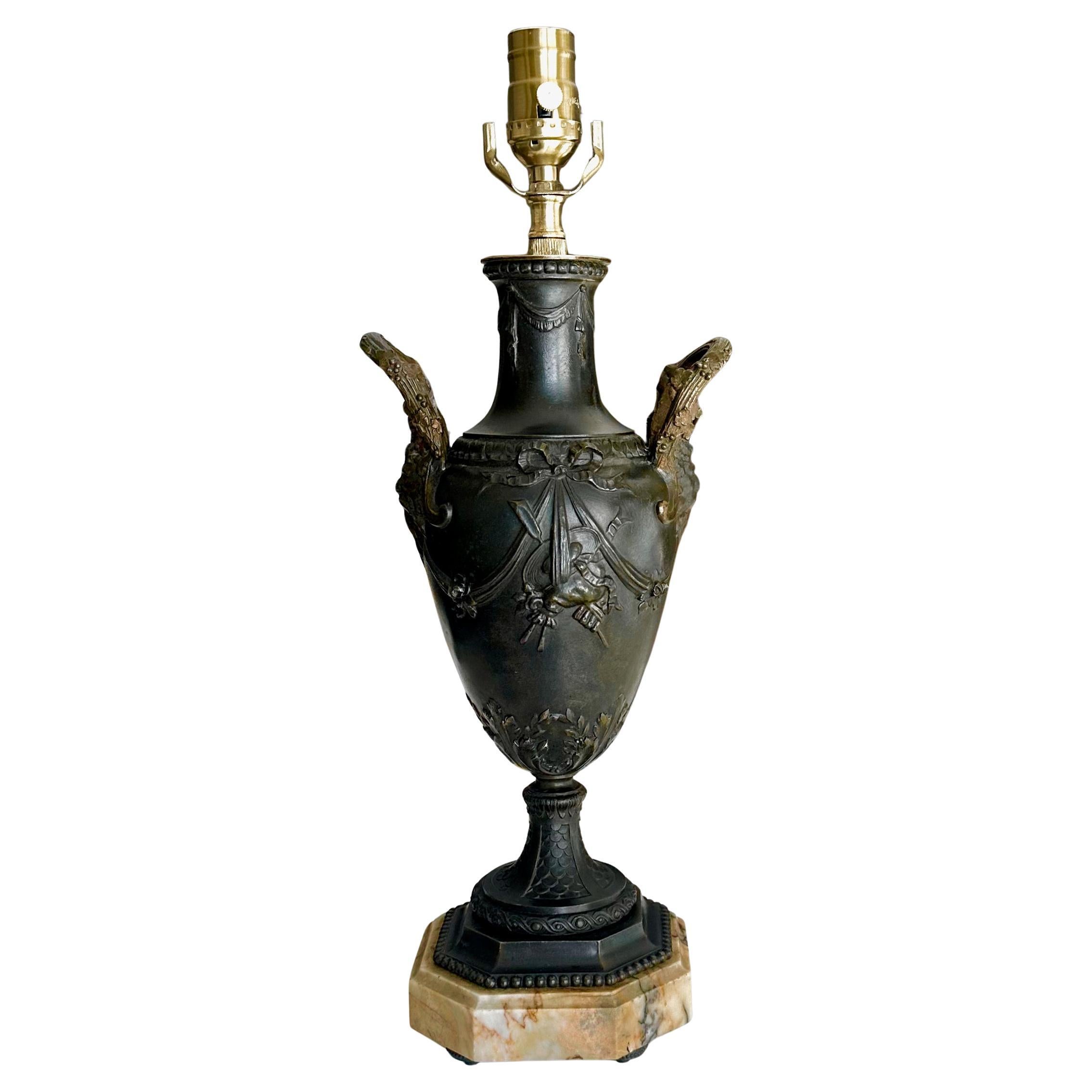 Single antique Napoleon III era table lamp made from a mantle urn or vase. The lamp features handles shaped like Satyr heads, floral swags, and bows. The dark bronze patinated finish is made of spelter (zinc alloy) that is expertly cast with fine
