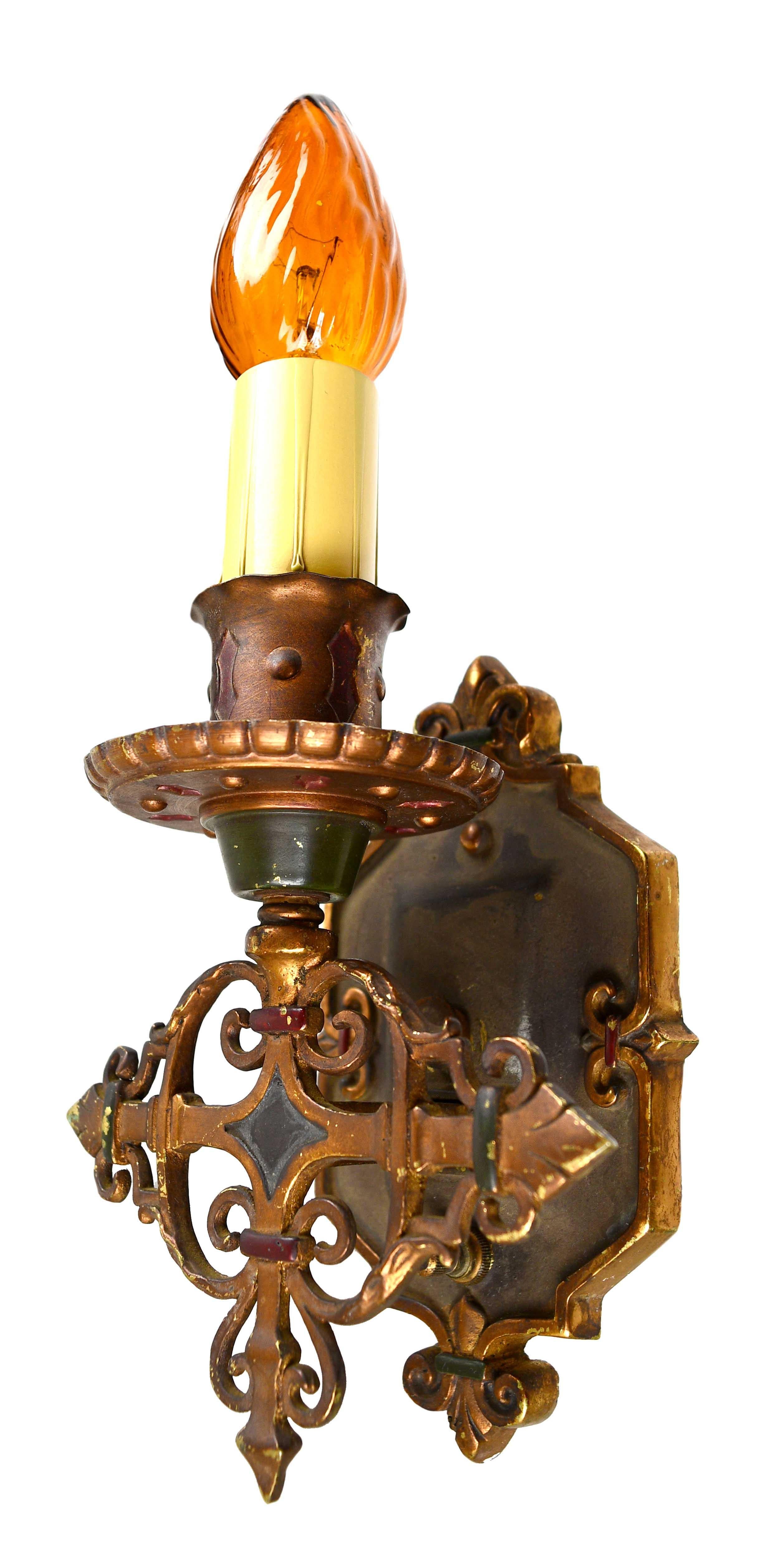 These finely crafted single candle sconces feature lovely polychrome detailing within the handsome brass metalwork, 

circa 1920s
Condition: Good
Material: Brass
Finish: Original
Country of origin: USA
Illumination: 1 standard Edison socket.