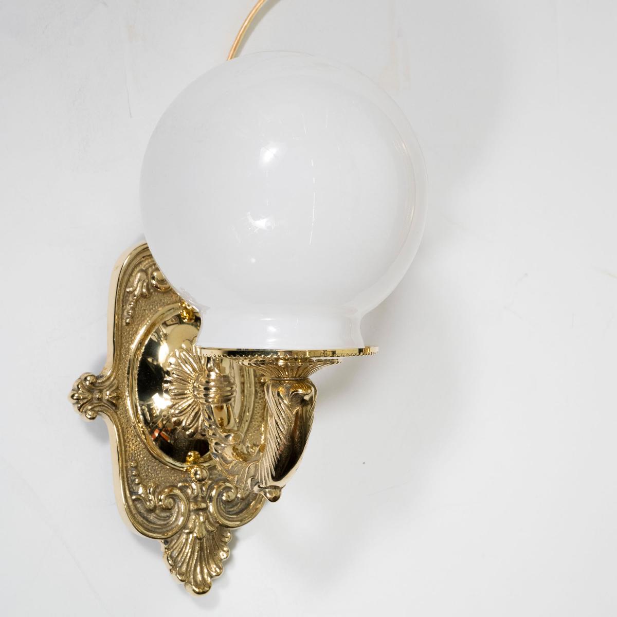 Single cast brass sconce with classic foliate, fleur de lis motif and white opaline glass globe shade.