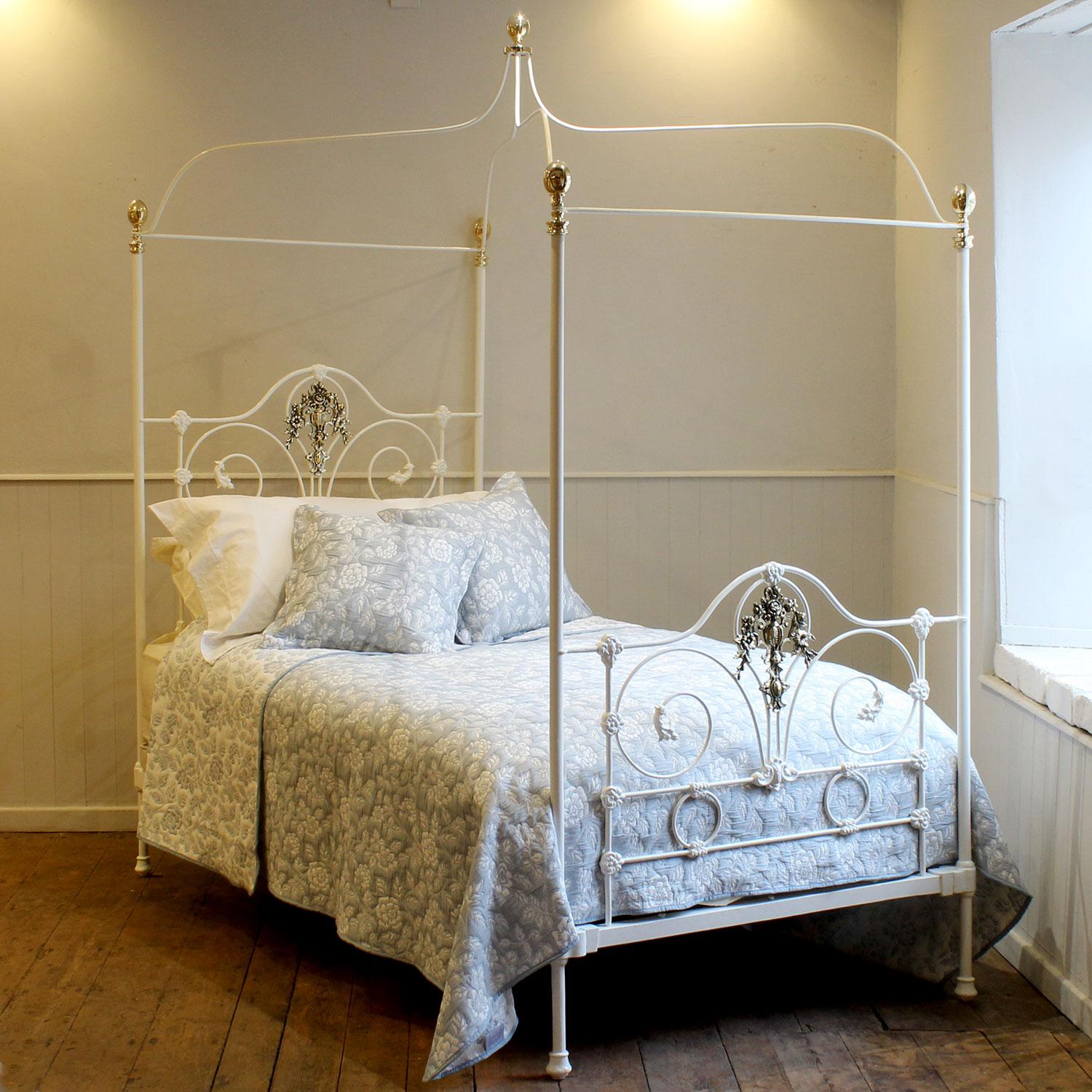 A superb and rare single antique four poster bed with crown and canopy, dating from the late Nineteenth Century. This delicate piece has ornate panels at the head and foot, with decorative castings and central brass plaque depicting an urn with