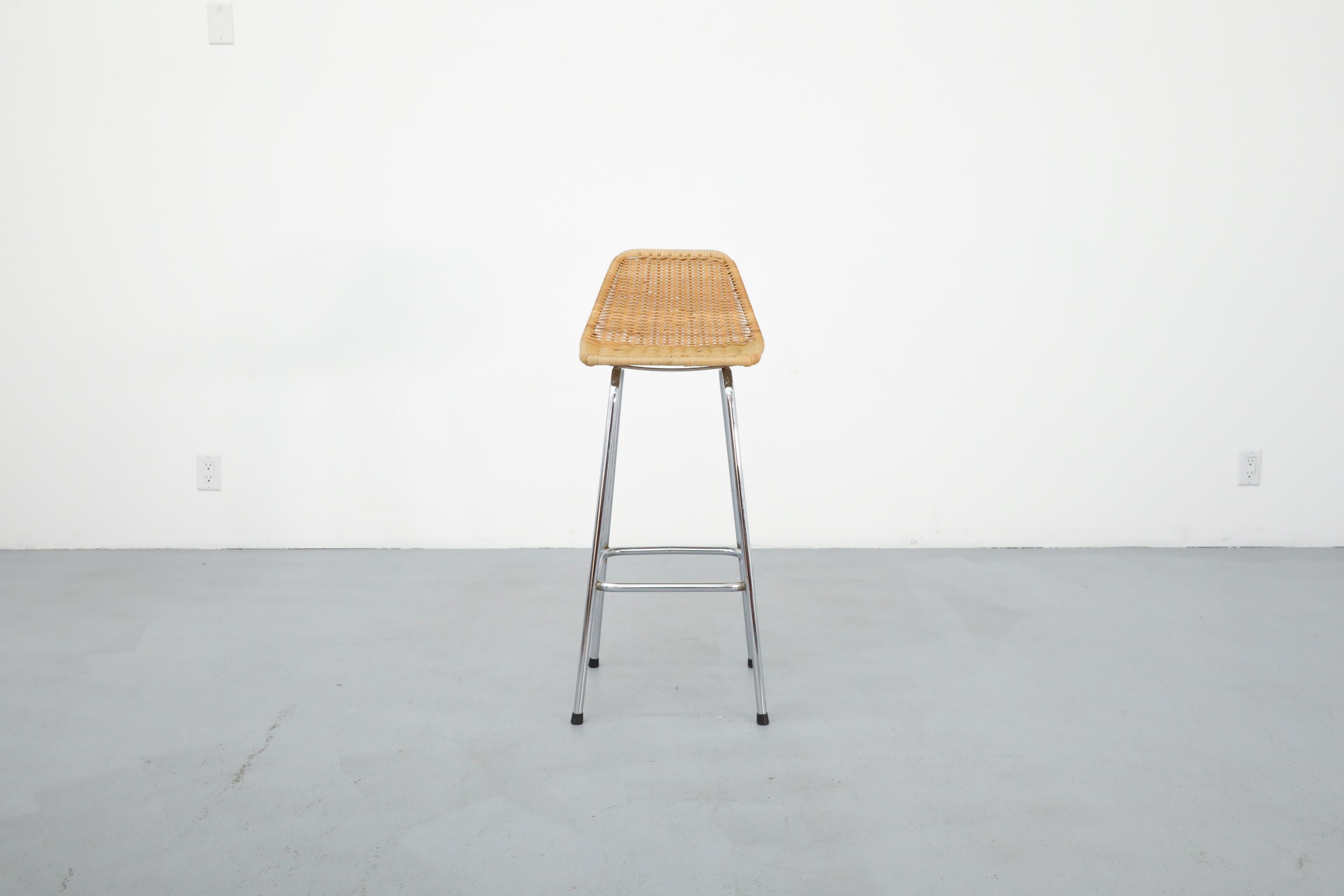 Tabouret de bar en osier de style Charlotte Perriand par Rohe Noordwolde. Ce tabouret a des pieds chromés, une assise en osier tressé et un dossier angulaire. En état original avec une usure visible correspondant à son âge et à son utilisation.