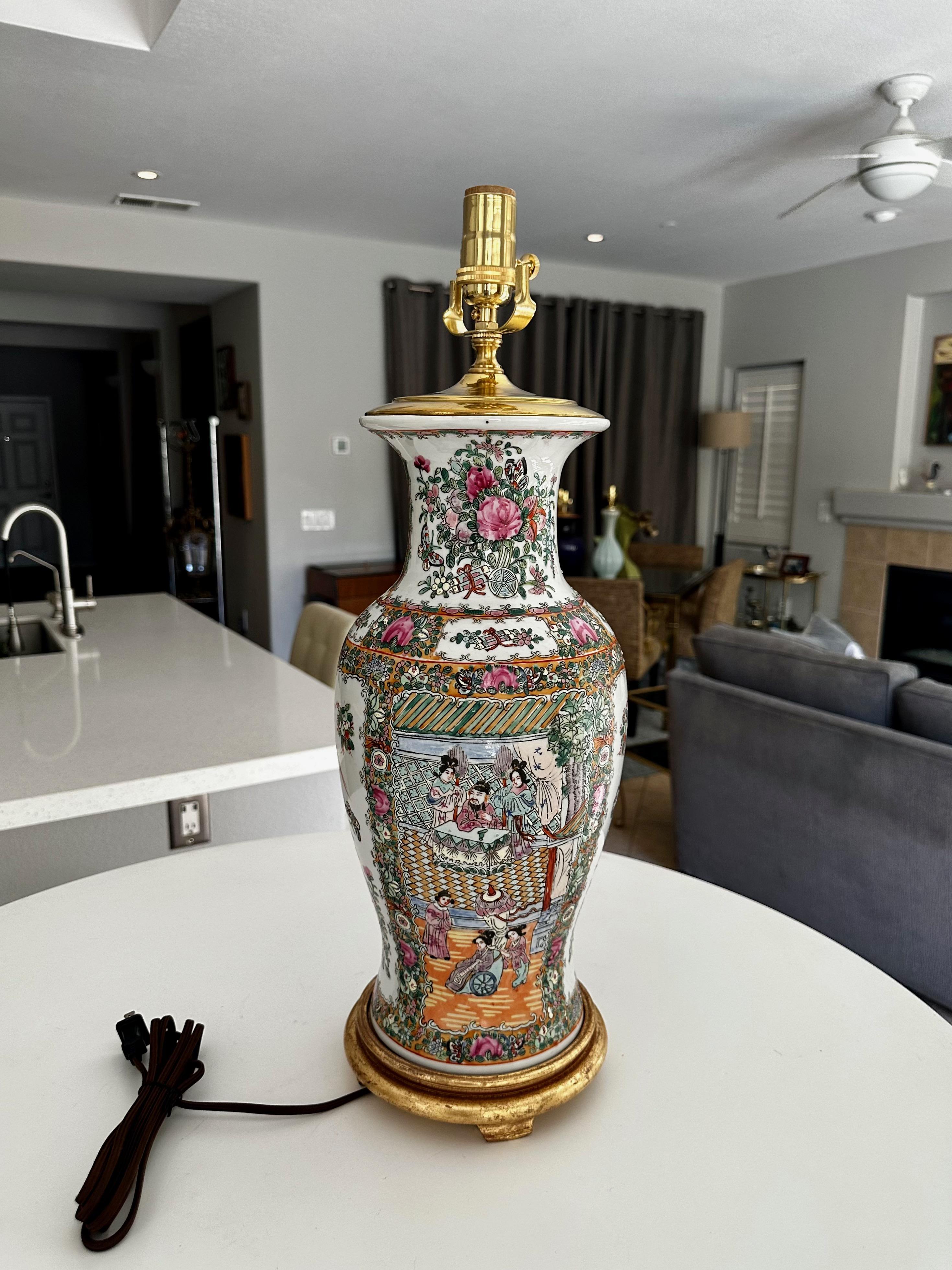 Vase Famille rose en porcelaine chinoise monté en lampe de table, base tournée en bois doré. Magnifiquement réalisé avec des images peintes de couleurs vives, dont la scène de la cour de l'empereur, des papillons, des oiseaux et des fleurs. Le
