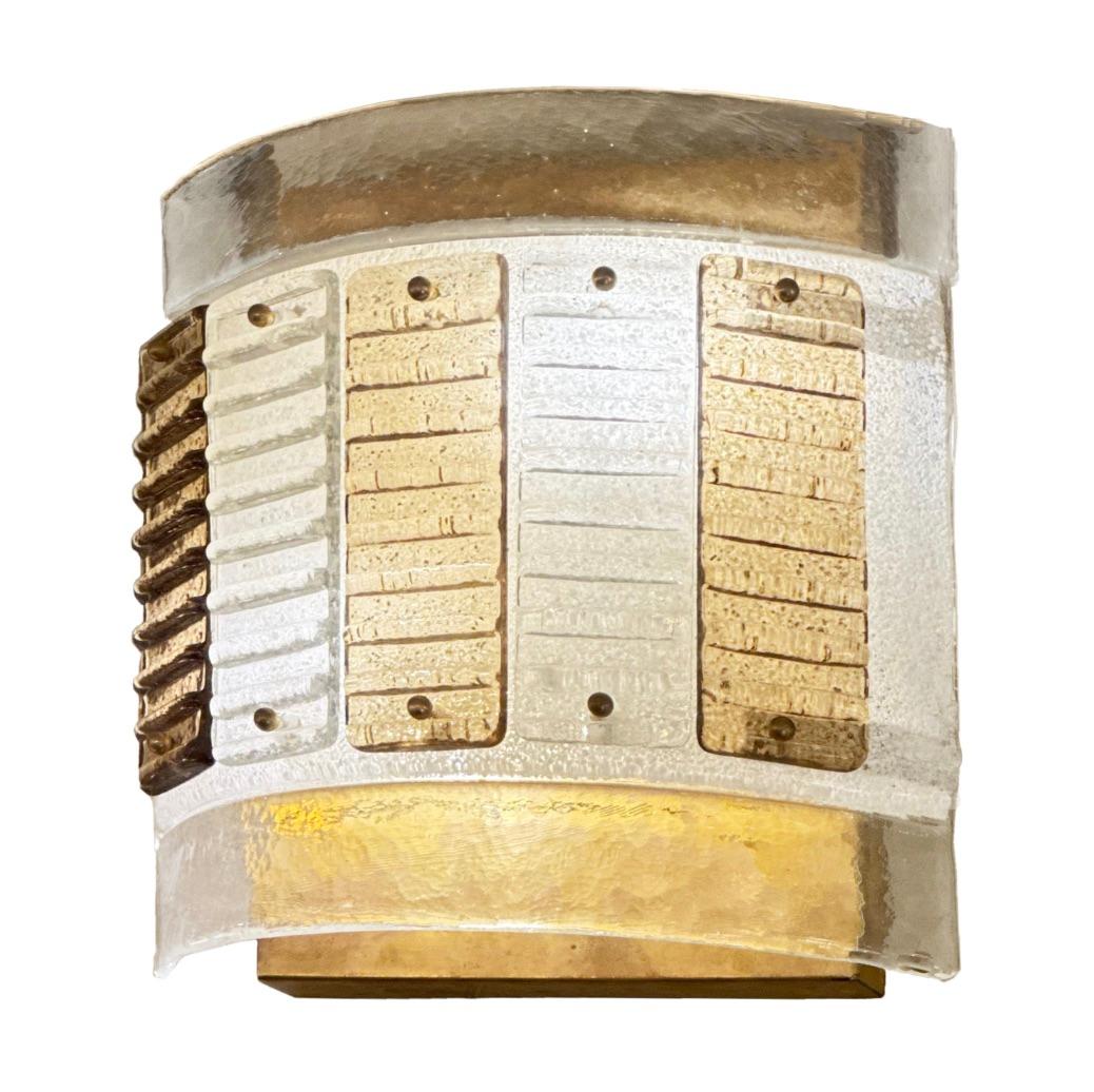 The simple and neat appearence of this handsome  single sconce looks as if it was tailored. Perfect for a vestibule, hallway or walk in closet. A curved plate of textured clear glass backs five strips of curragated glass in shades of amber. The