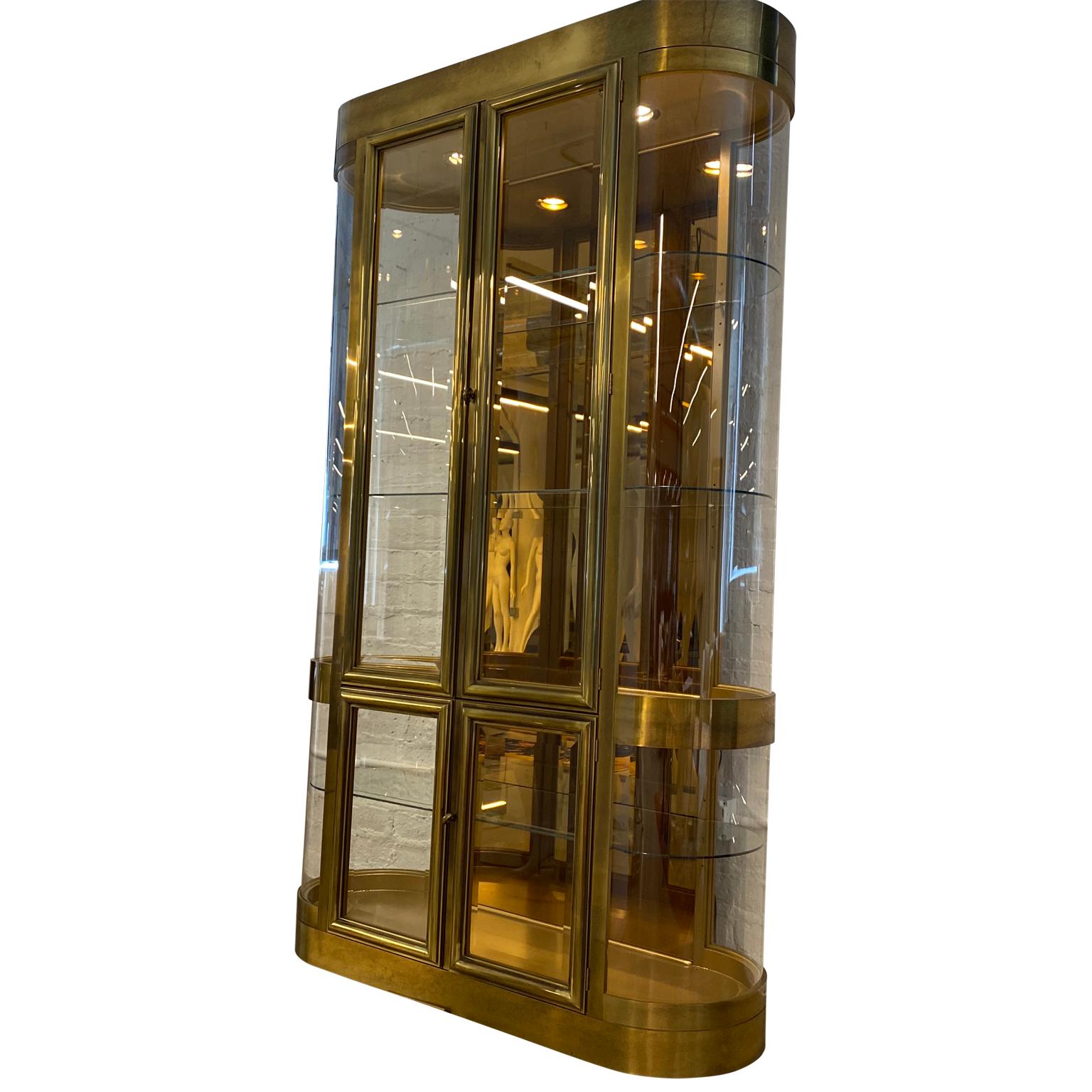 Rare single Mastercraft brass vitrine display cabinet with curved Lucite sides and with mirrored back, glass shelves and locking doors. The glass panels and door have thick bevelled glass.
The vitrine has working display lighting.

The inside depth