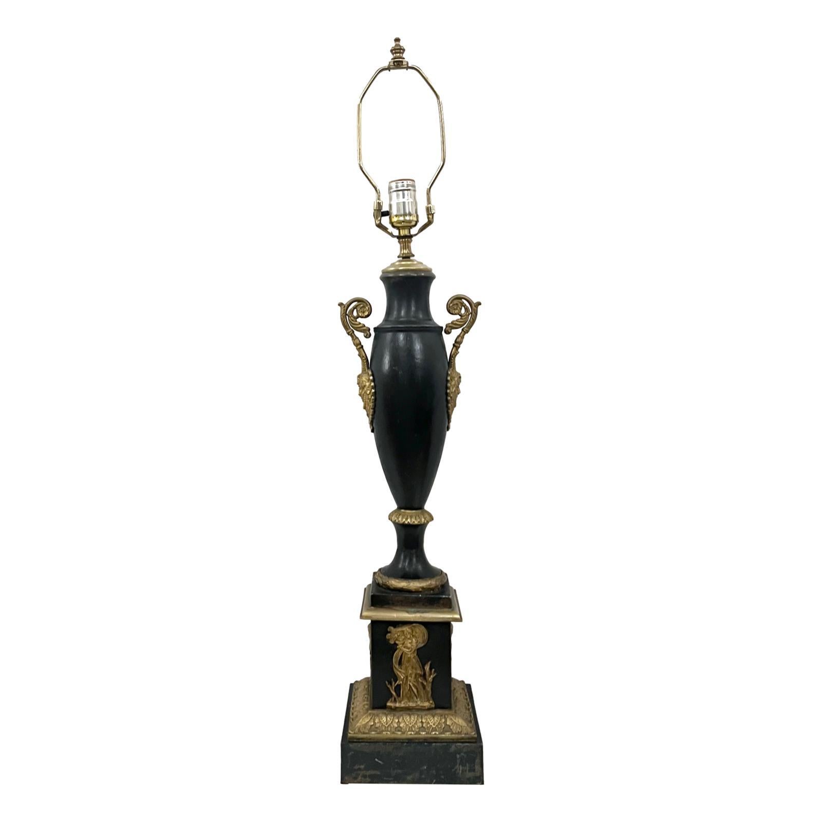 Lámpara de tole y bronce de estilo Imperio francés de hacia 1920, con cuerpo de tole pintado y detalles de bronce.

Medidas:
Altura del cuerpo: 23.5
Altura hasta el apoyo de la sombrilla: 31.5
Diámetro: 6