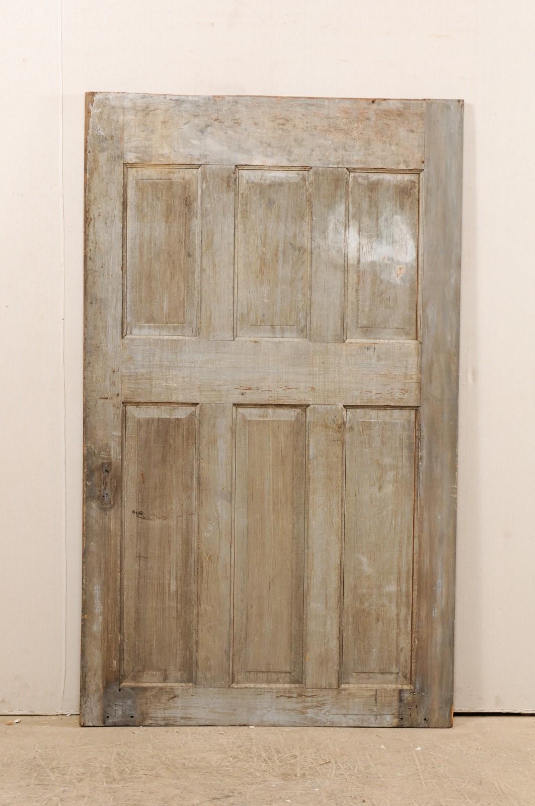 A single European 19th century six-panel wood door. This antique door with nicely-sized width features six raised panels at both front and back sides. Each door has three shorter vertically positioned rectangular-shaped panels sitting directly about