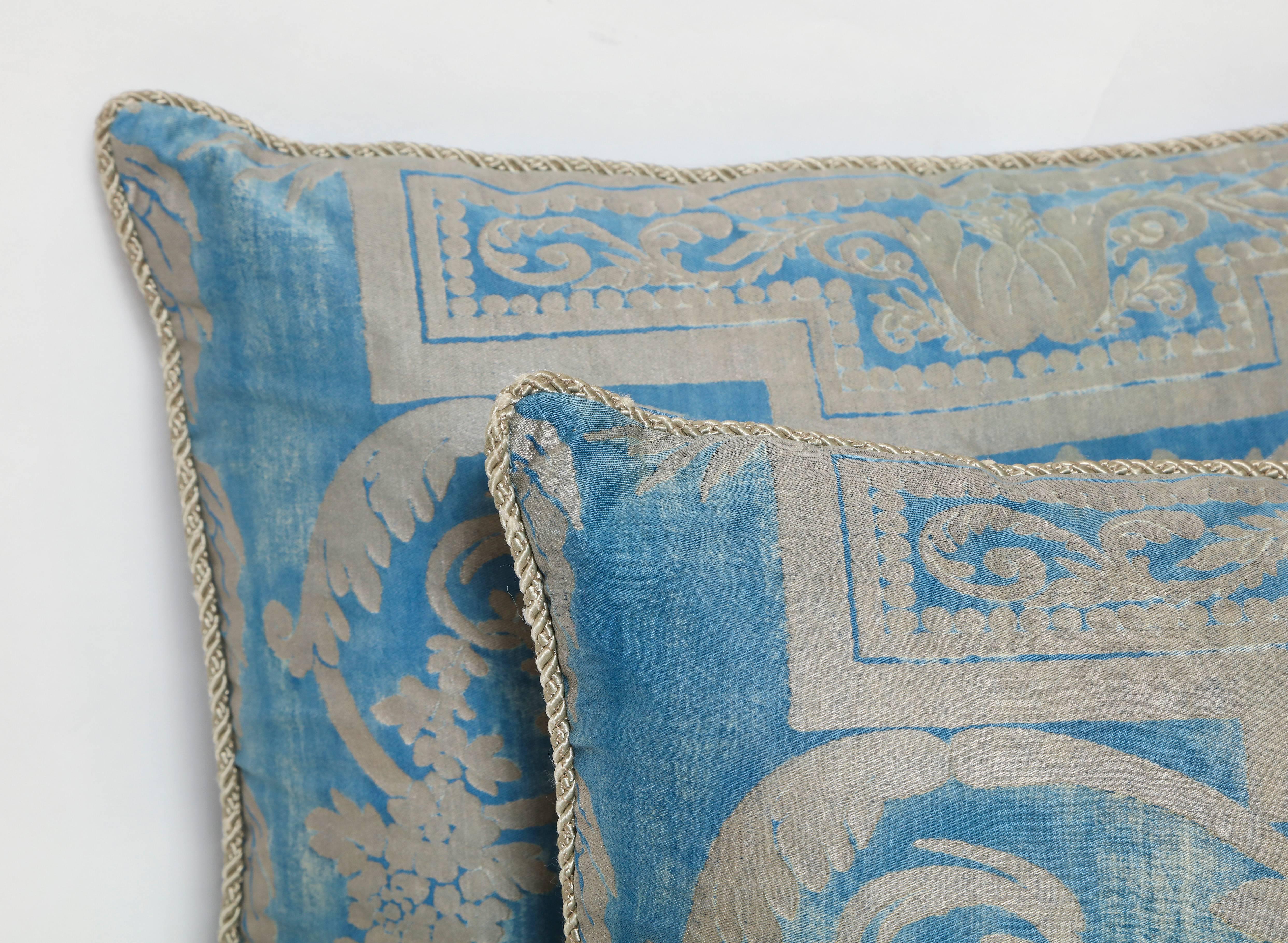 A Fortuny silk pillow cushion in metallic blue and silver fabric depicting a neoclassical design with a draped garland motif, with braided trim and woven back.
50 down/50 feather insert.
Newly made using vintage Fortuny fabric, circa 1930.
 
