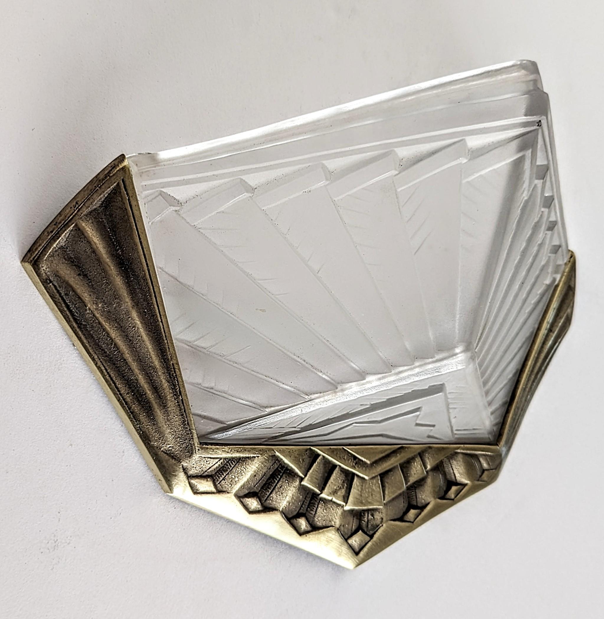 A single French Art Deco wall sconce signed by E J G  ( signature shown on the last image). Clear frosted molded glass shade in geometric design held by matching golden frame, in great condition. Sconce has been rewired for U.S. standards. Sconce