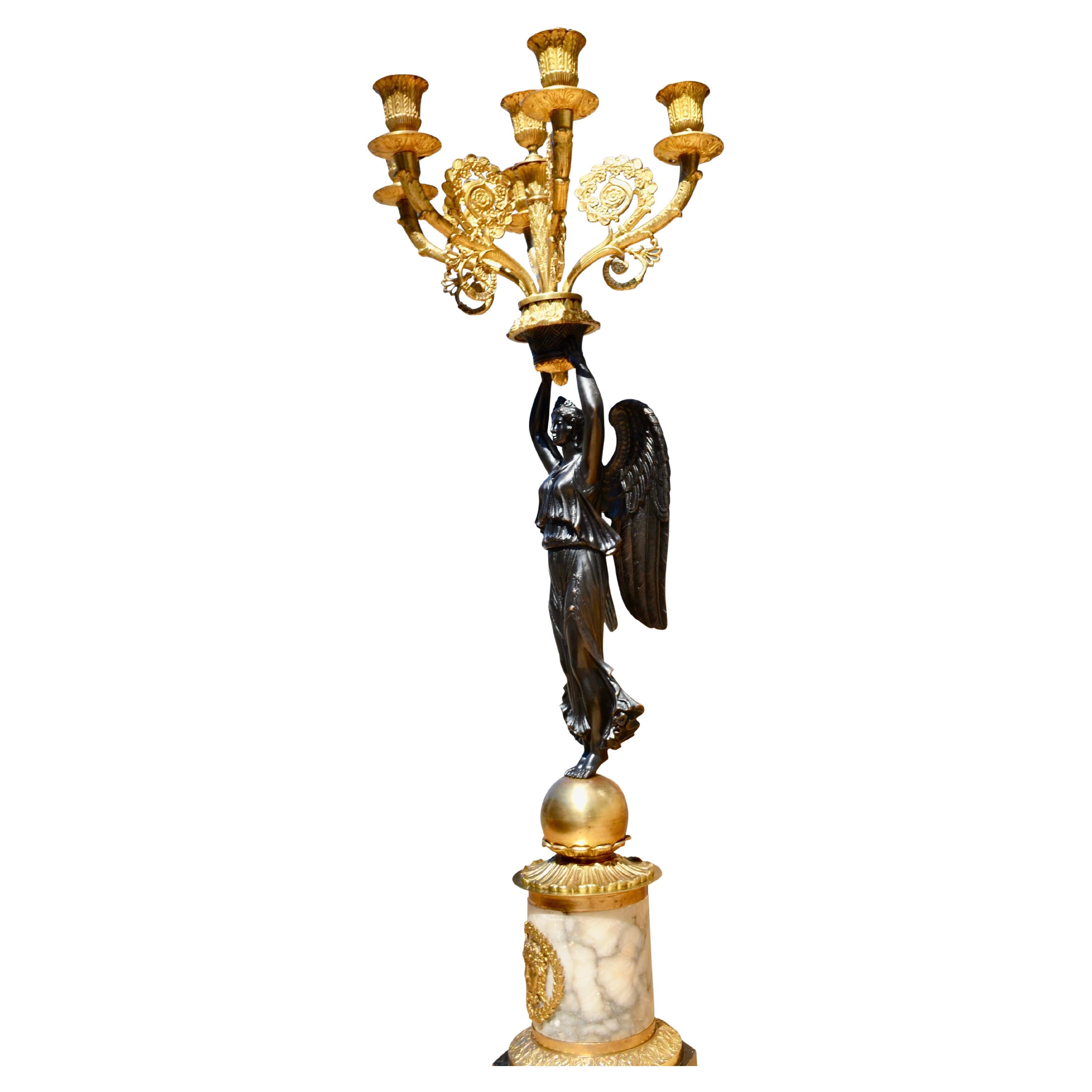 A mid to late 19thC French Empire style candelabra that at one time was electrified. A finely chased patinated winged Nike or Winged Victory stands on a gilt ball and holds aloft five gilt candle arms and a central candle stem, the whole resting on